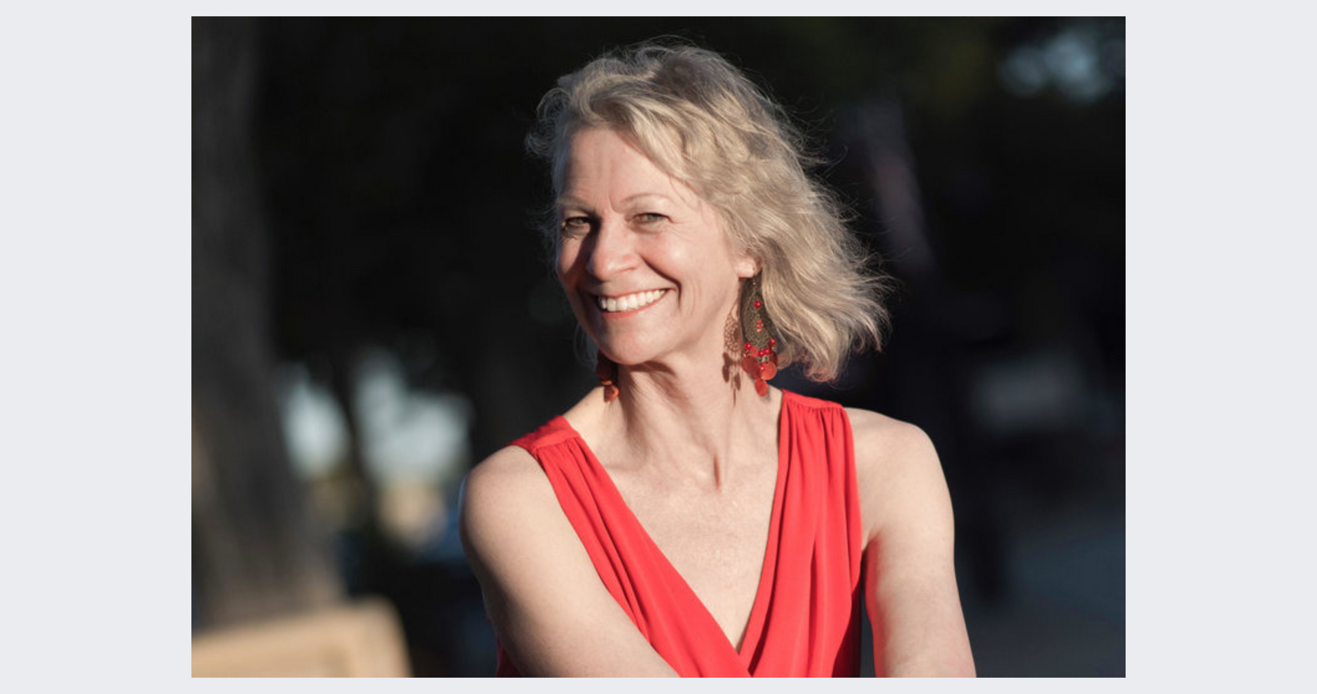 A woman in a red dress is smiling and looking at the camera.