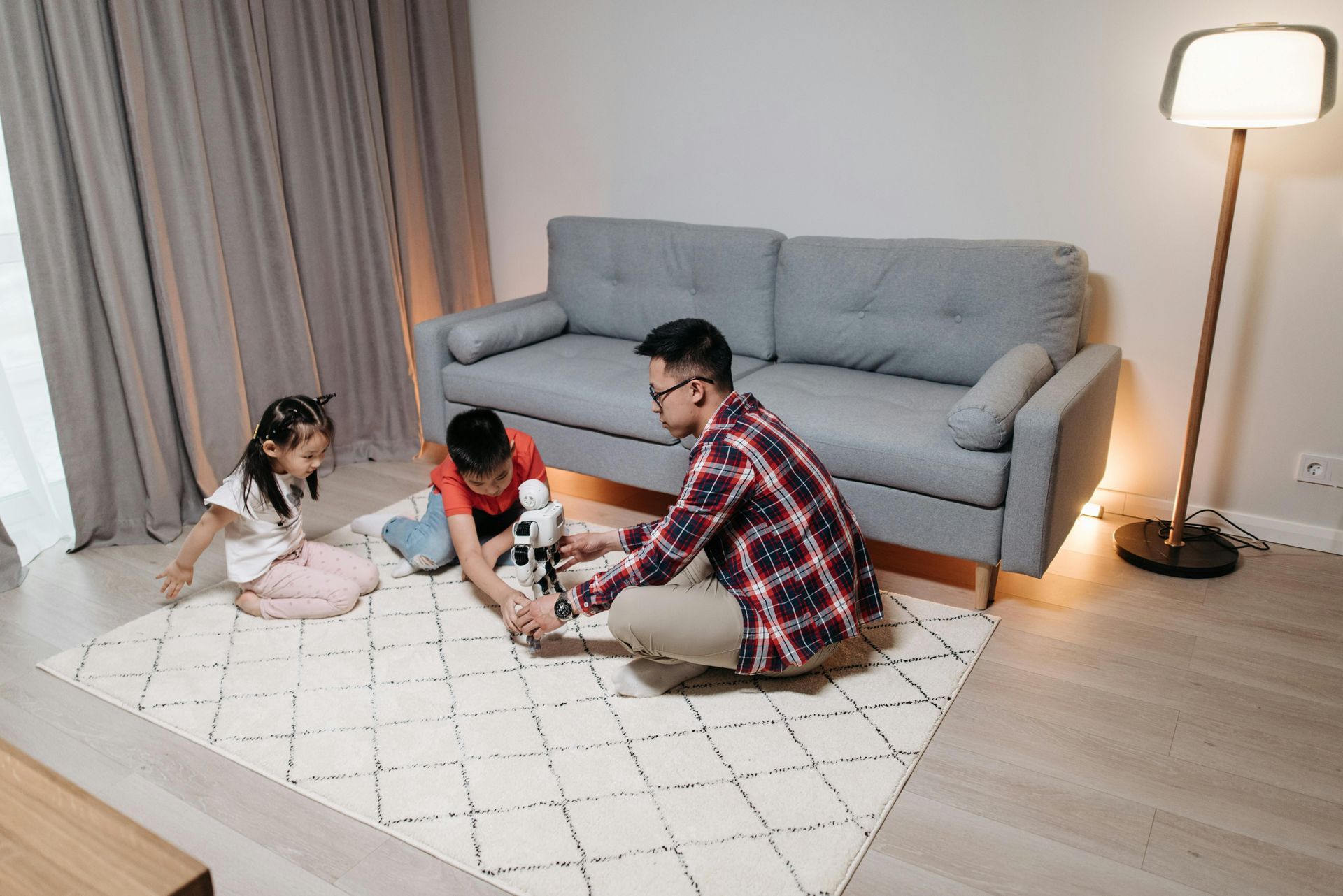 Father and children build a robot together on a rug in their living room.