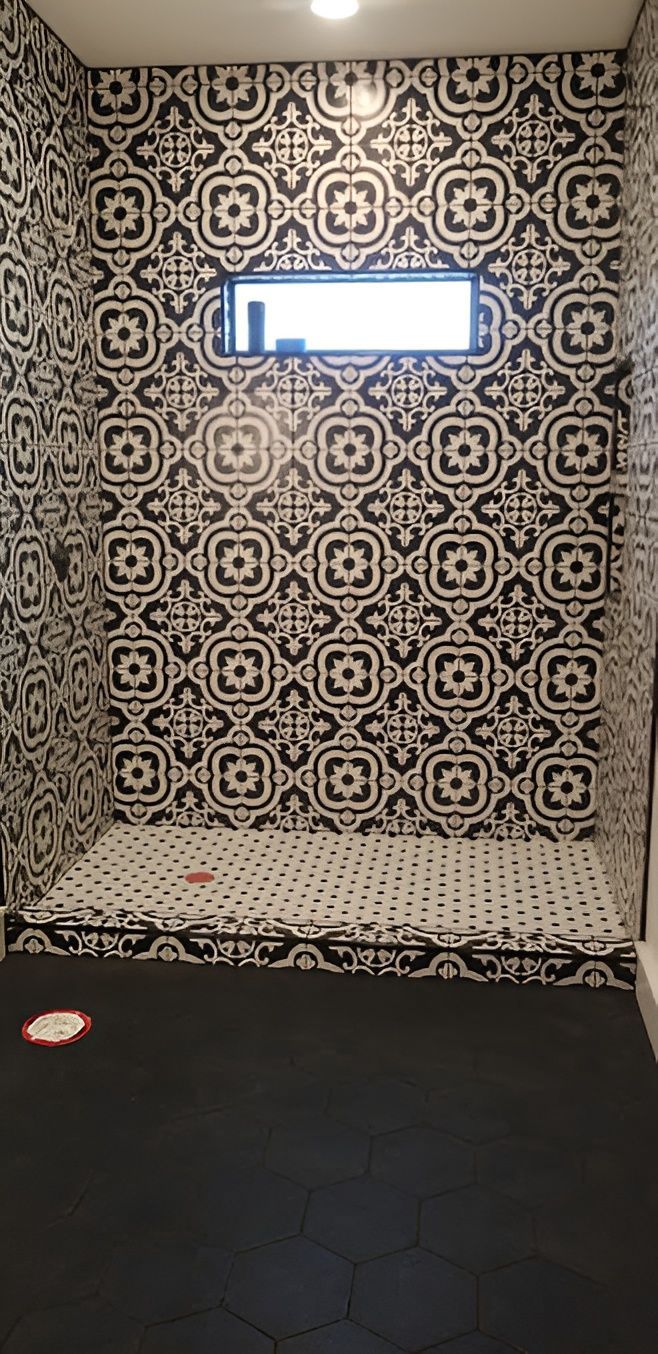 Shower with black and white patterned tiles on the walls and floor, with a small window.