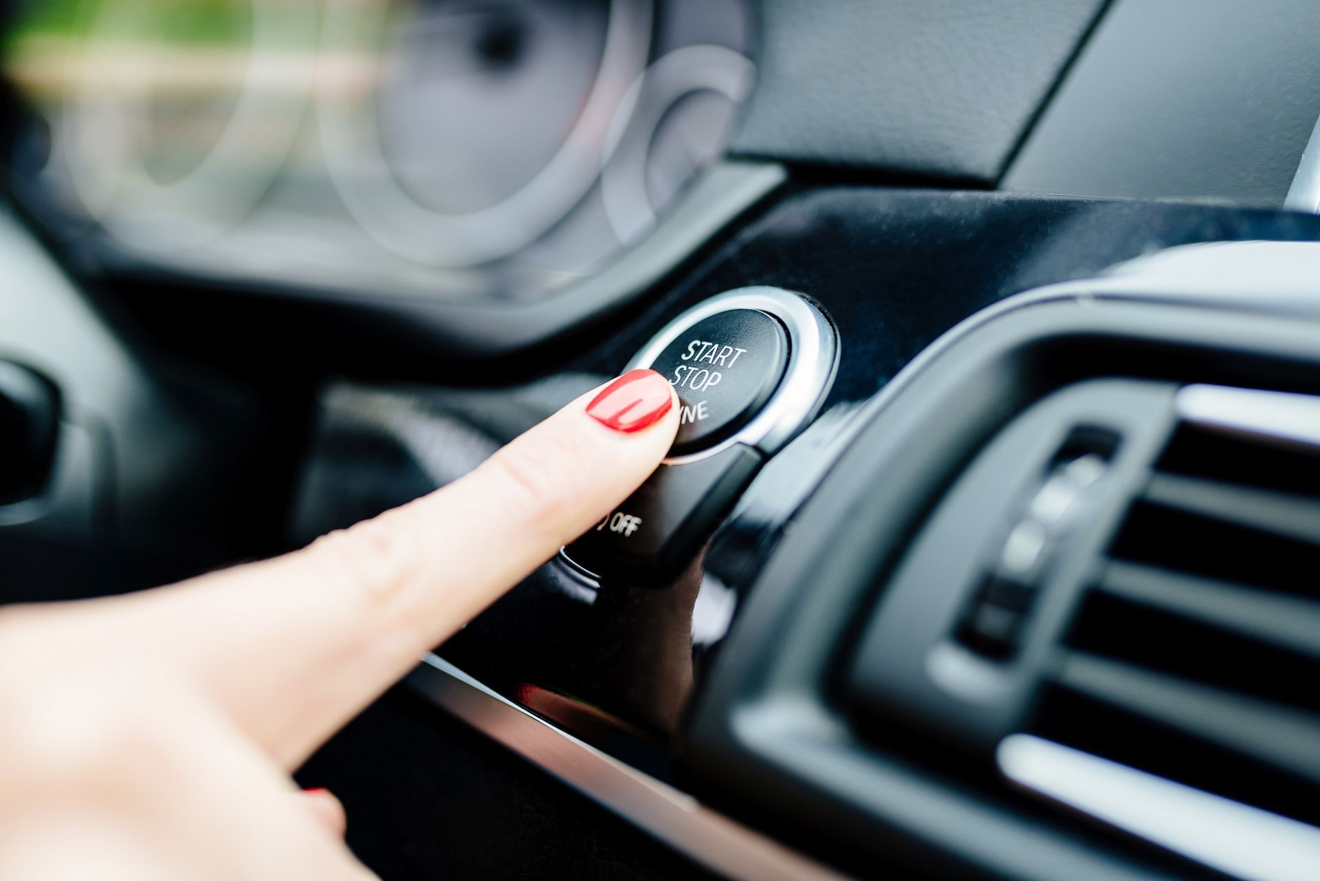 A woman is pressing a button on the dashboard of a car.