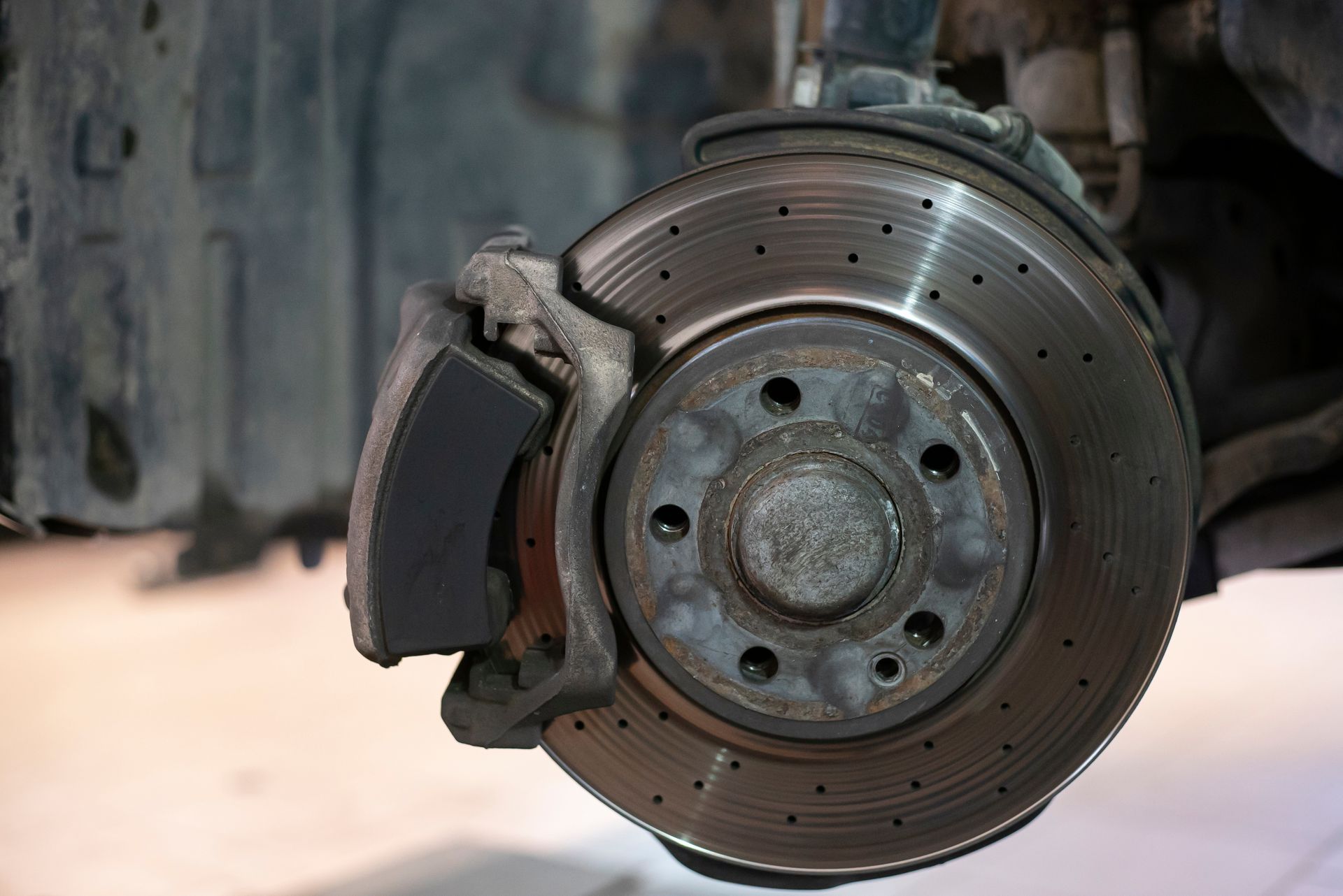 Close-up of a car brake rotor and caliper with visible wear and rust.