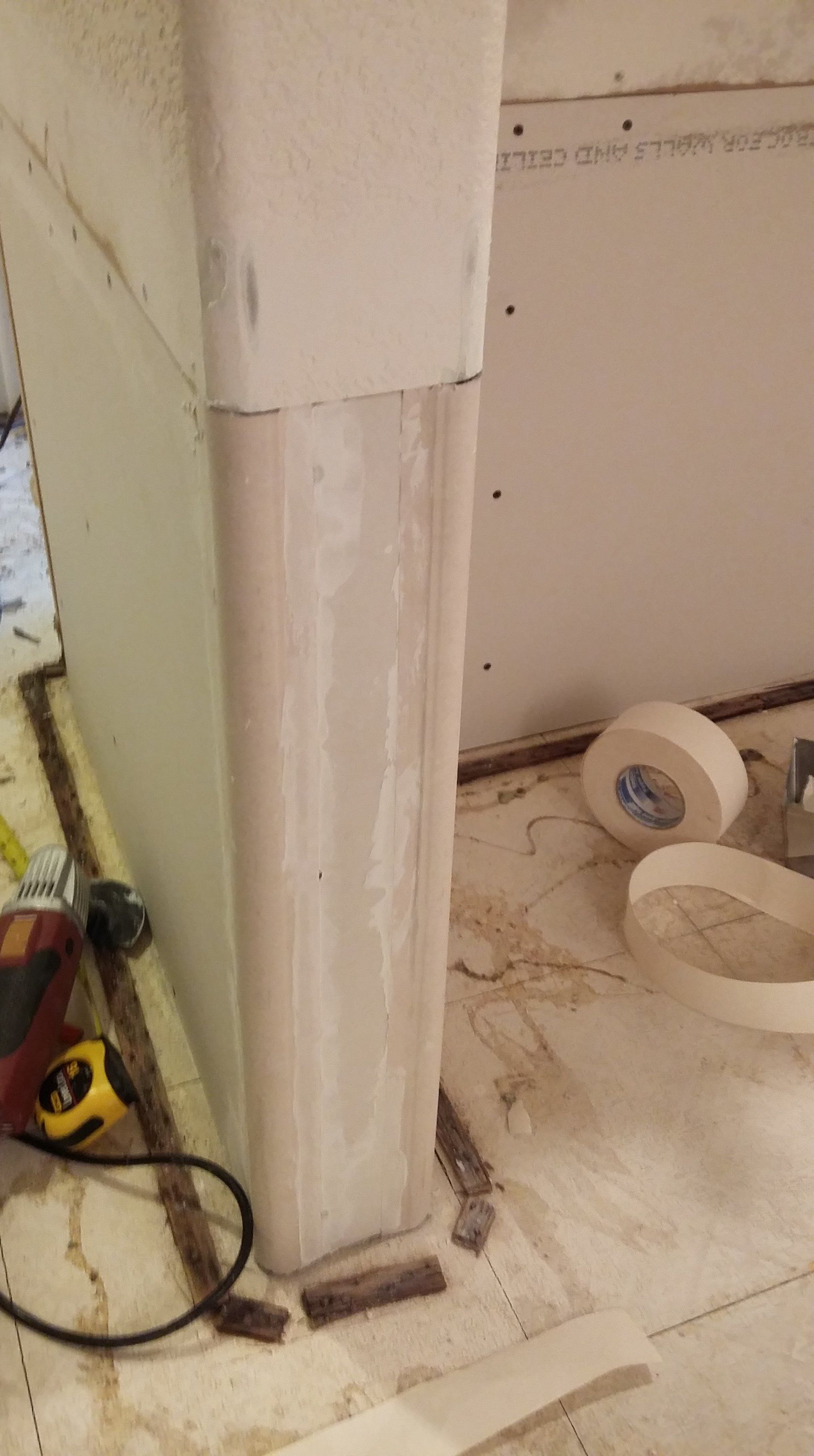 A roll of tape is sitting on the floor next to a wall.