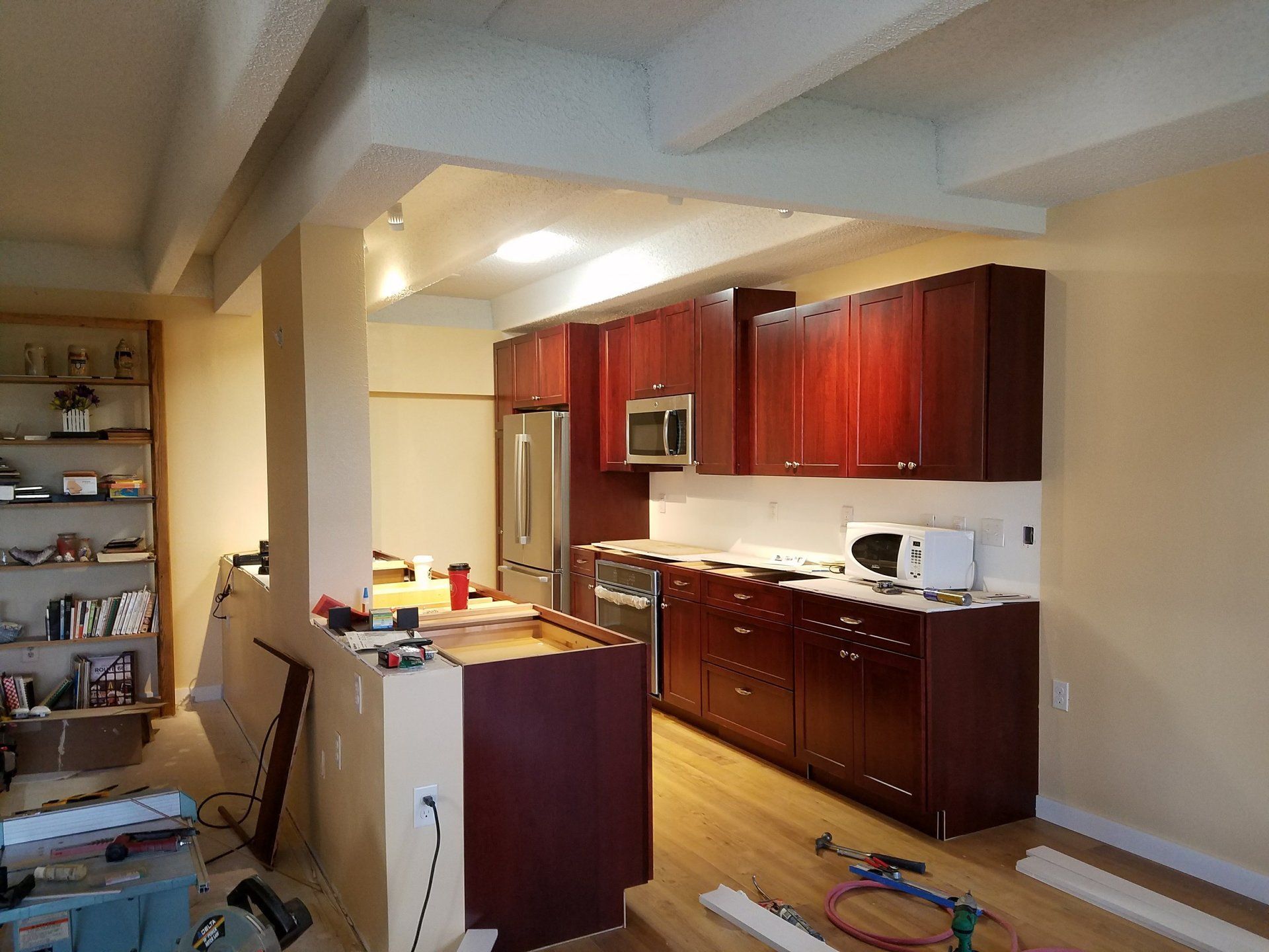 A kitchen is being remodeled with wooden cabinets and stainless steel appliances