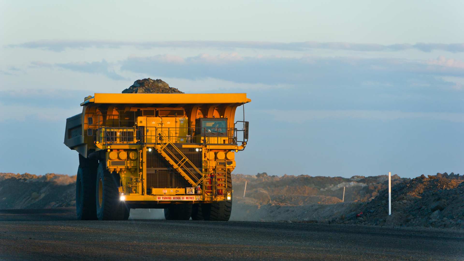 a large yellow dump truck is driving down a dirt road
