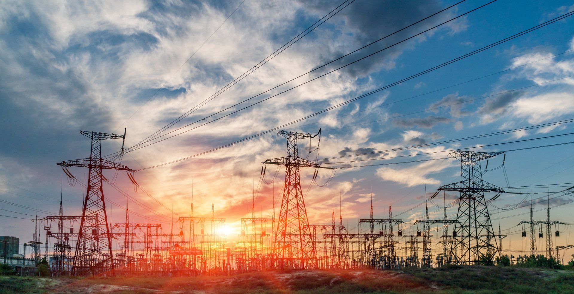 A row of power lines against a cloudy sky at sunset.