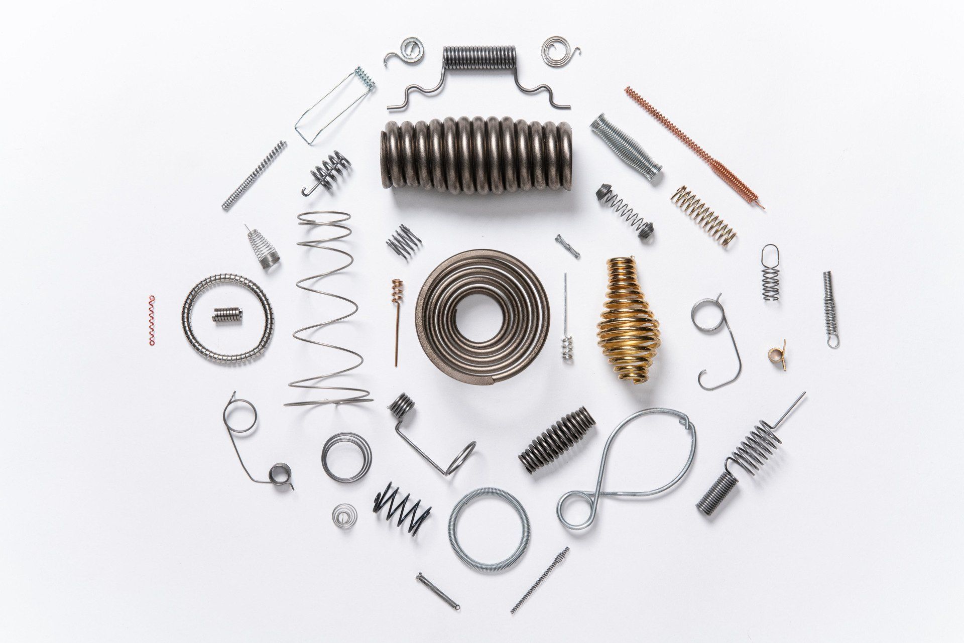 A bunch of different types of springs are arranged in a circle on a white surface.