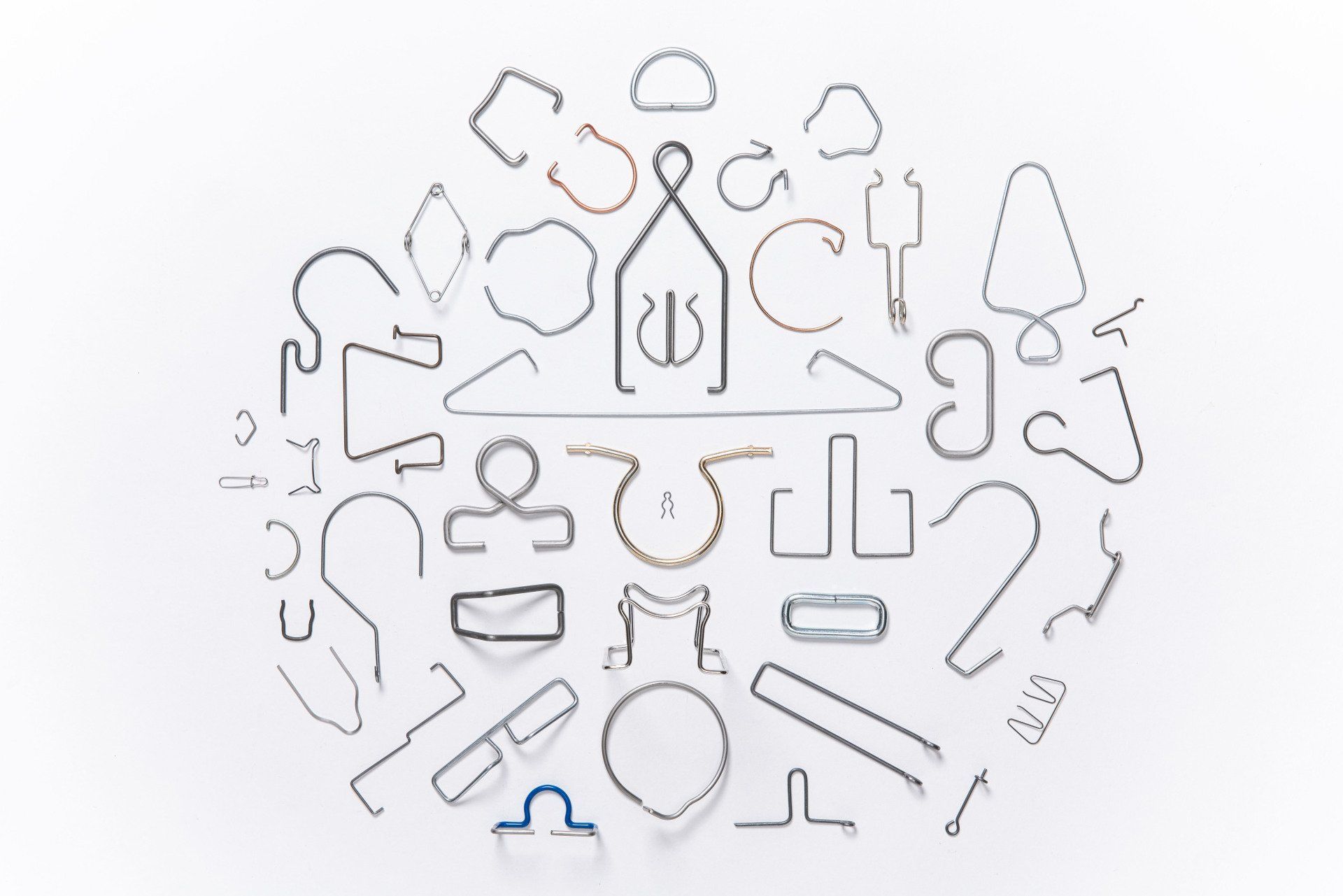 A bunch of different shaped metal wires are arranged in a circle on a white surface.