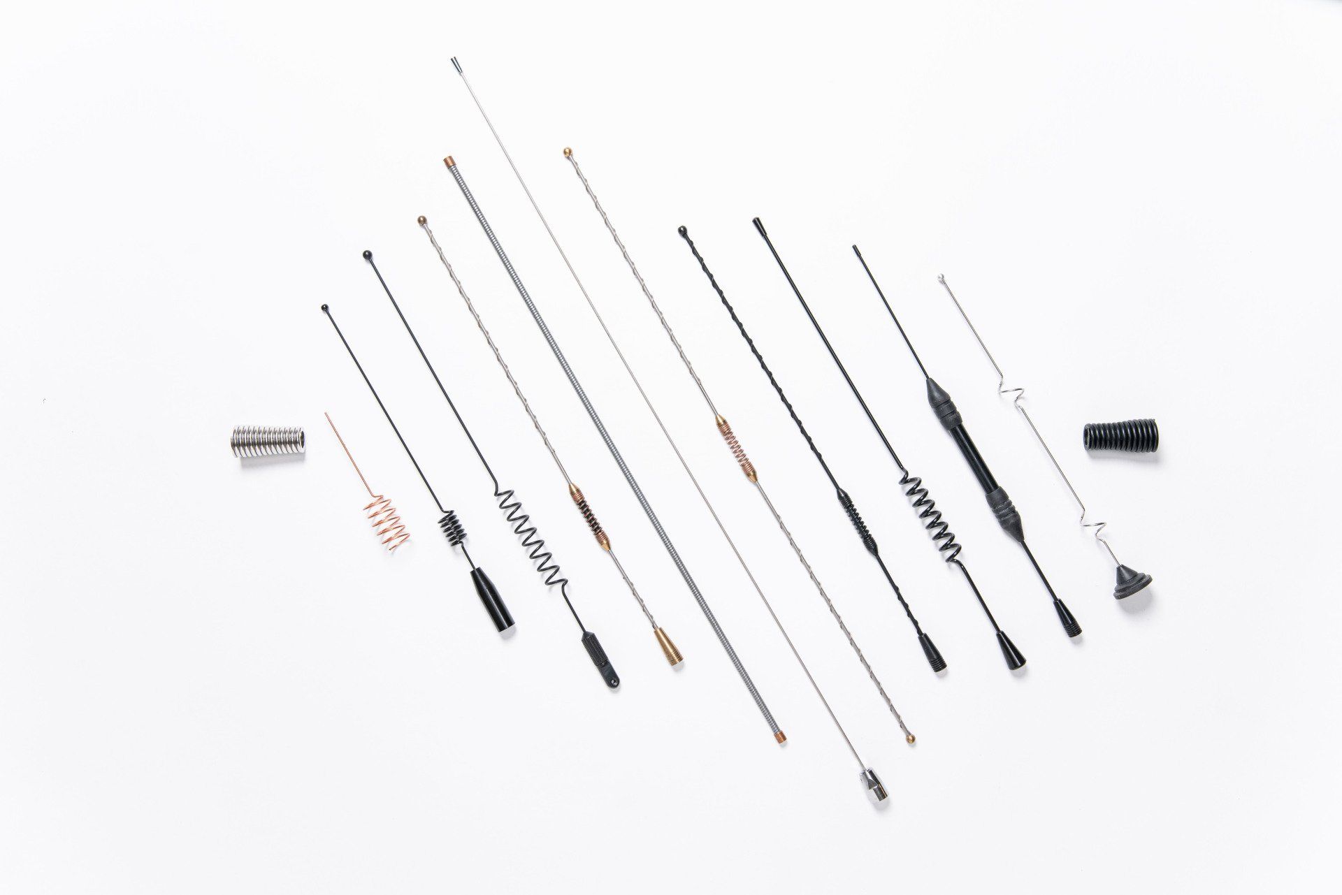A bunch of different types of antennas are lined up on a white surface.