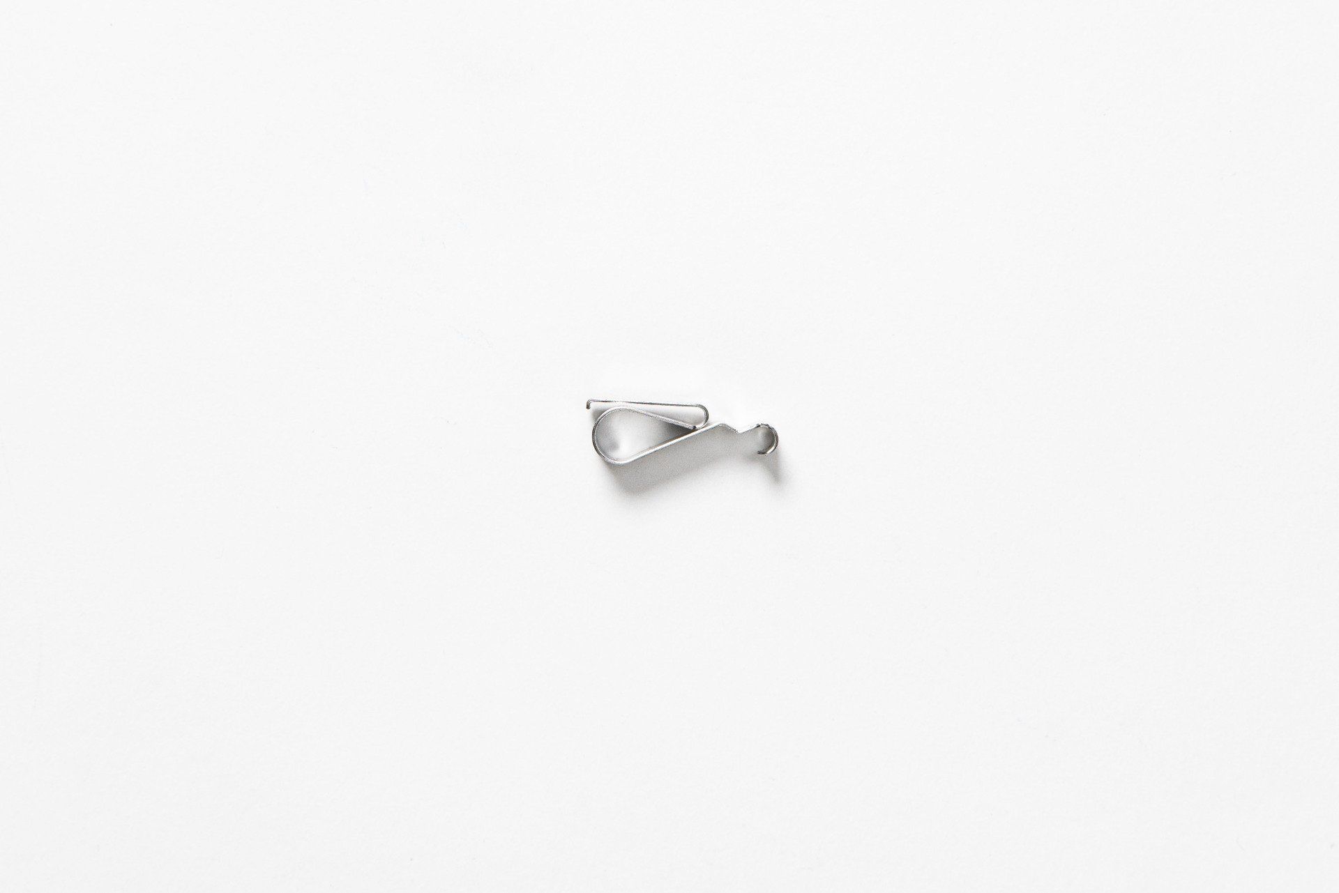A small silver pendant is sitting on a white surface.