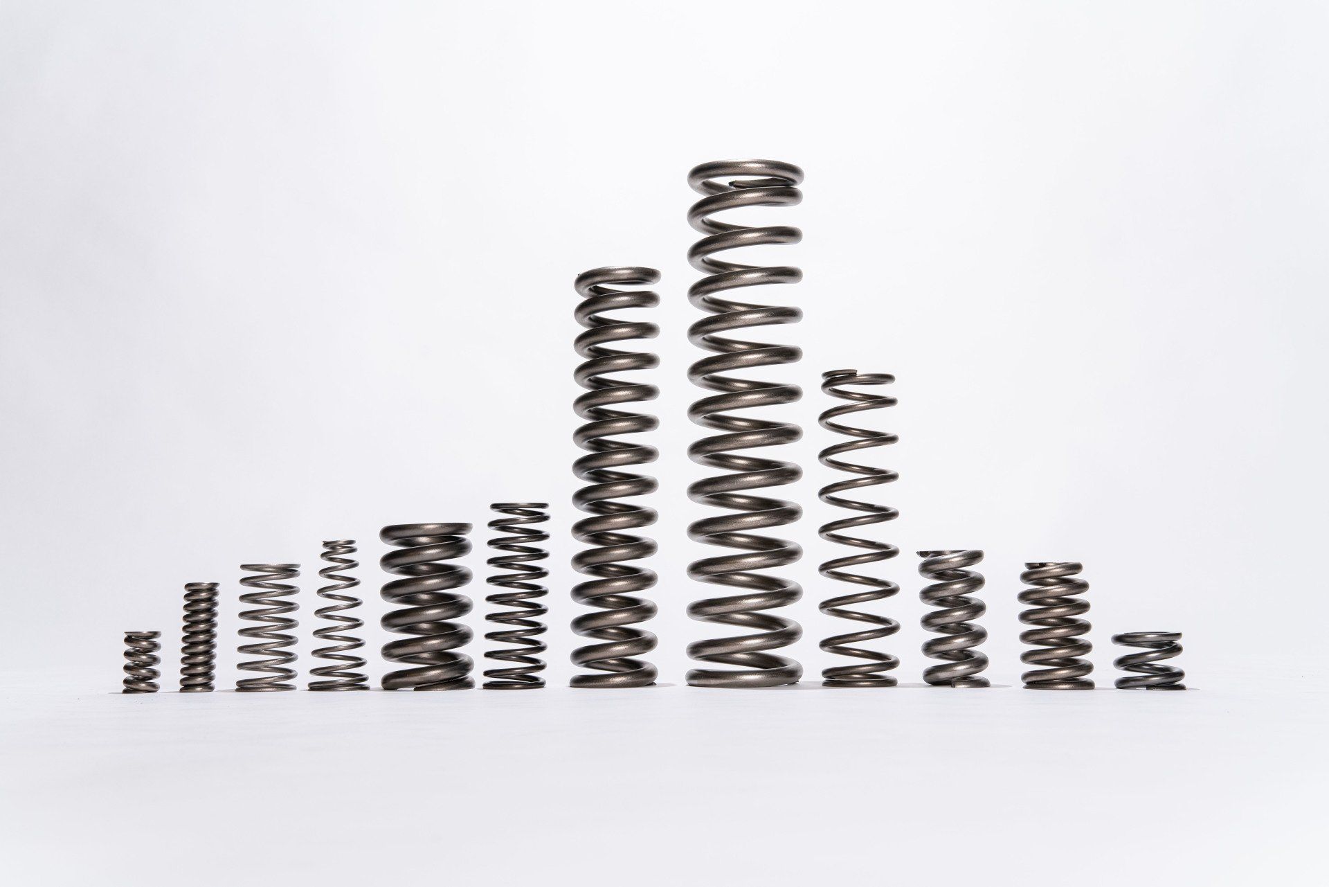 A bunch of different types of springs are stacked on top of each other on a white surface.