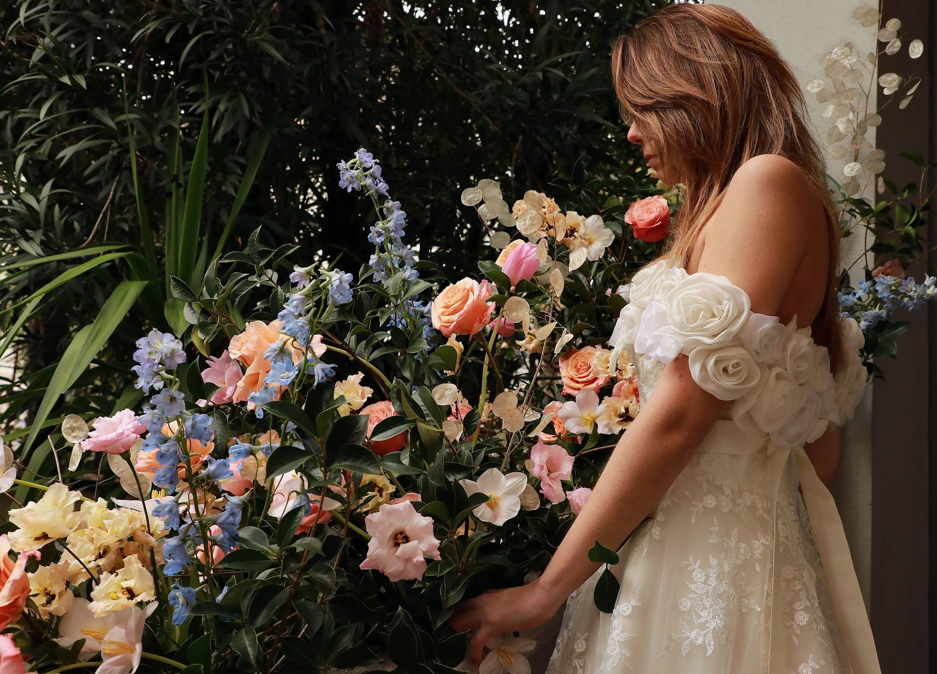 Una donna in abito da sposa è in piedi davanti a un mazzo di fiori.