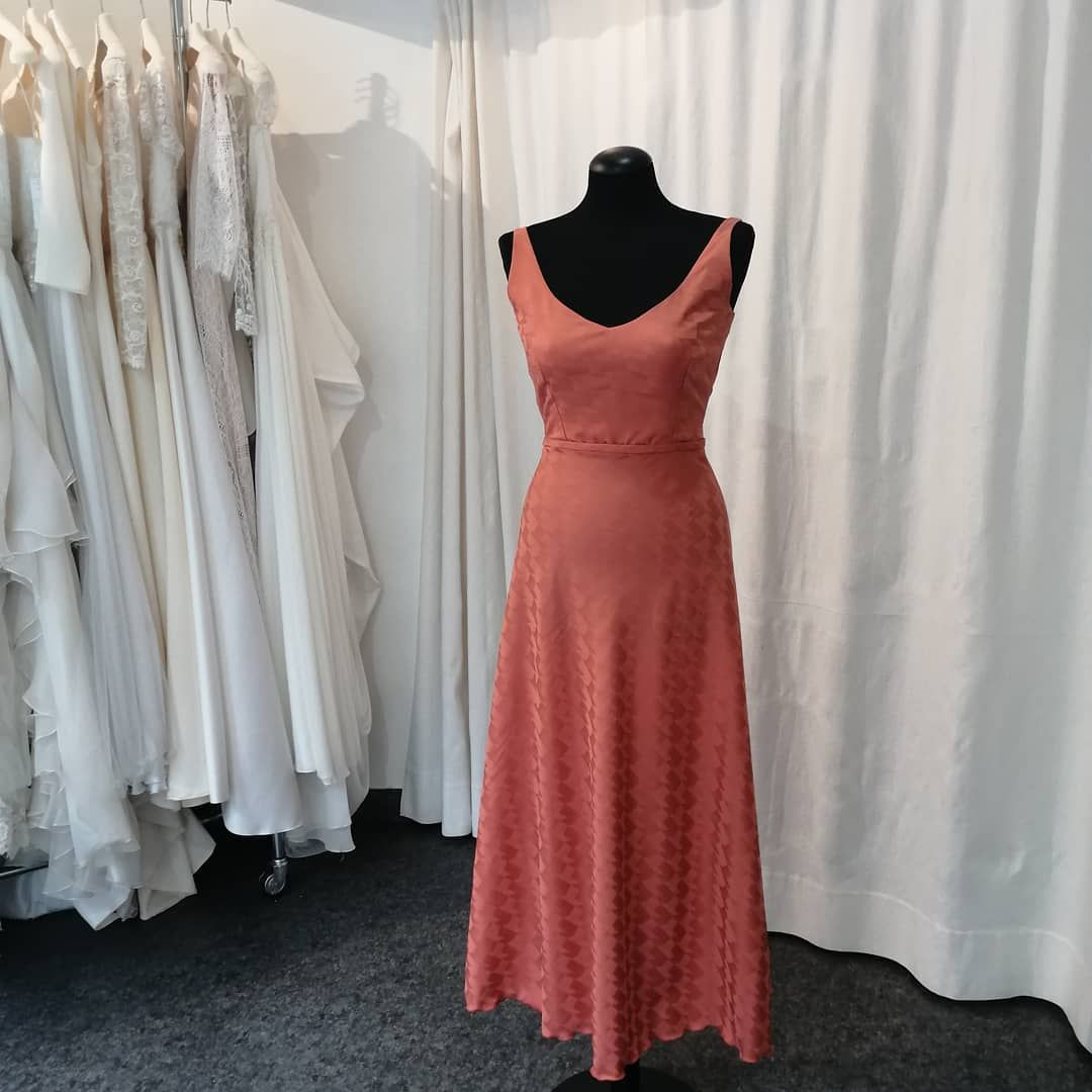 Un vestito rosso è su un manichino davanti a una tenda bianca