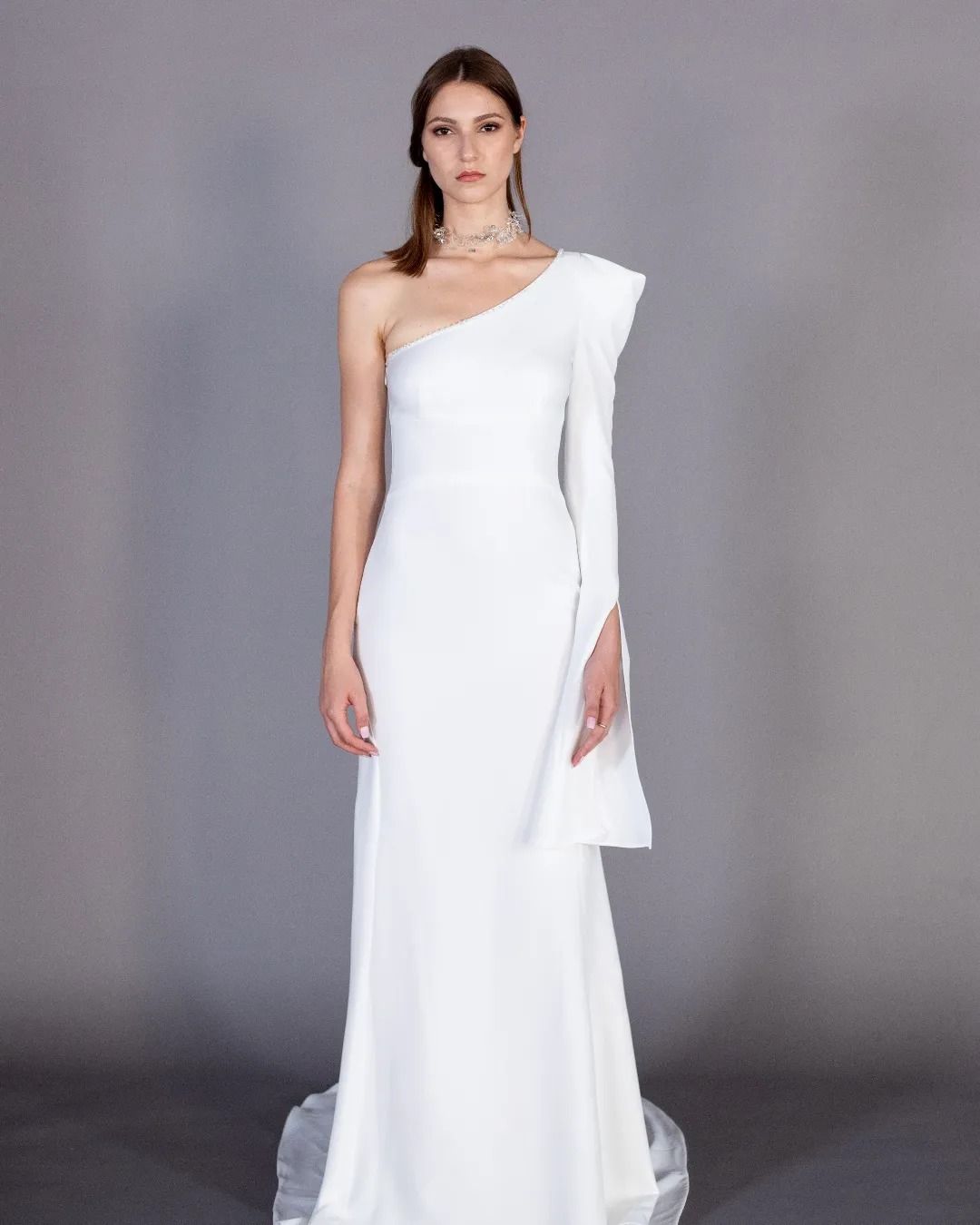 Una donna indossa un abito bianco monospalla.