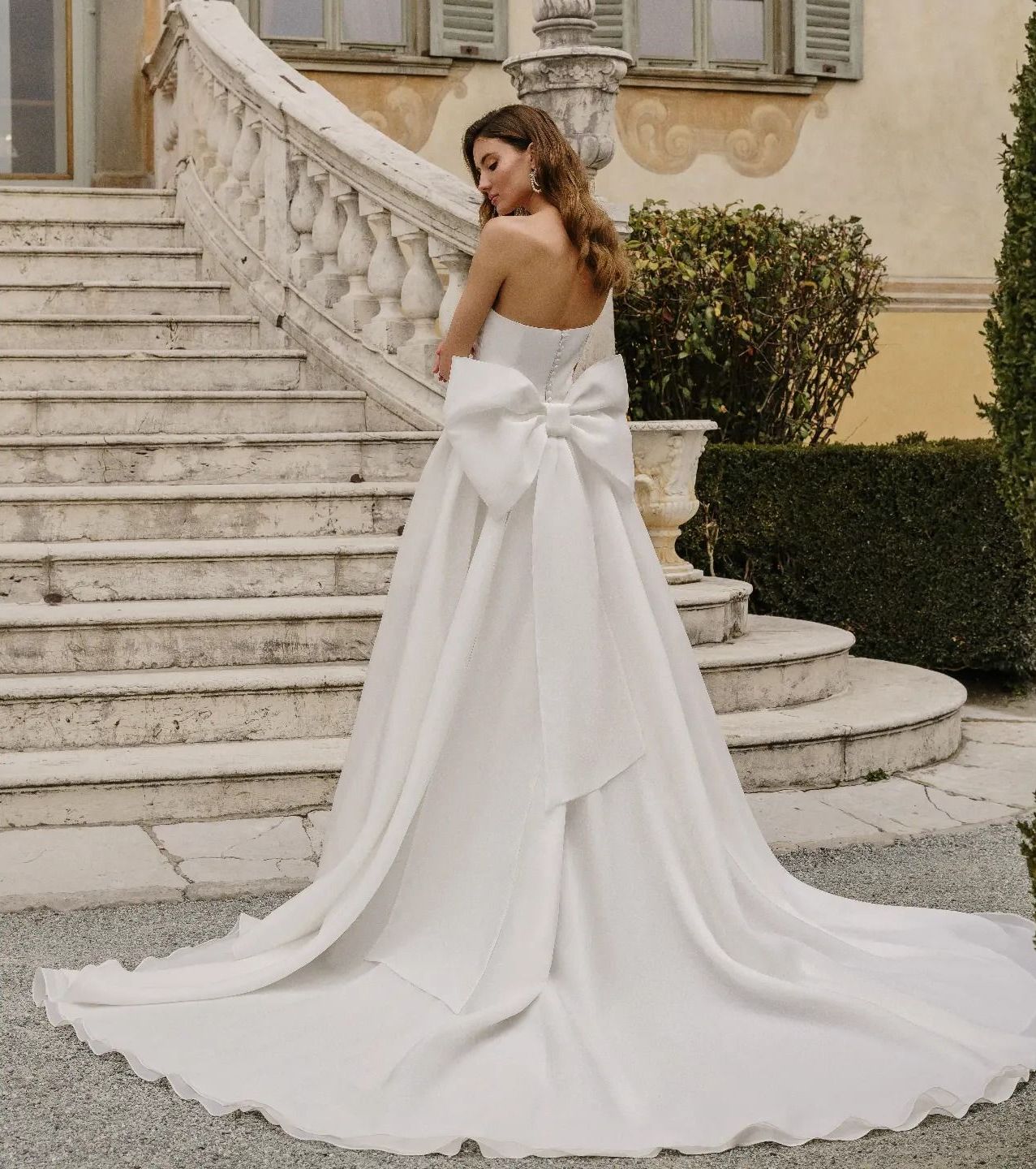 Una donna in abito da sposa bianco è in piedi sulle scale