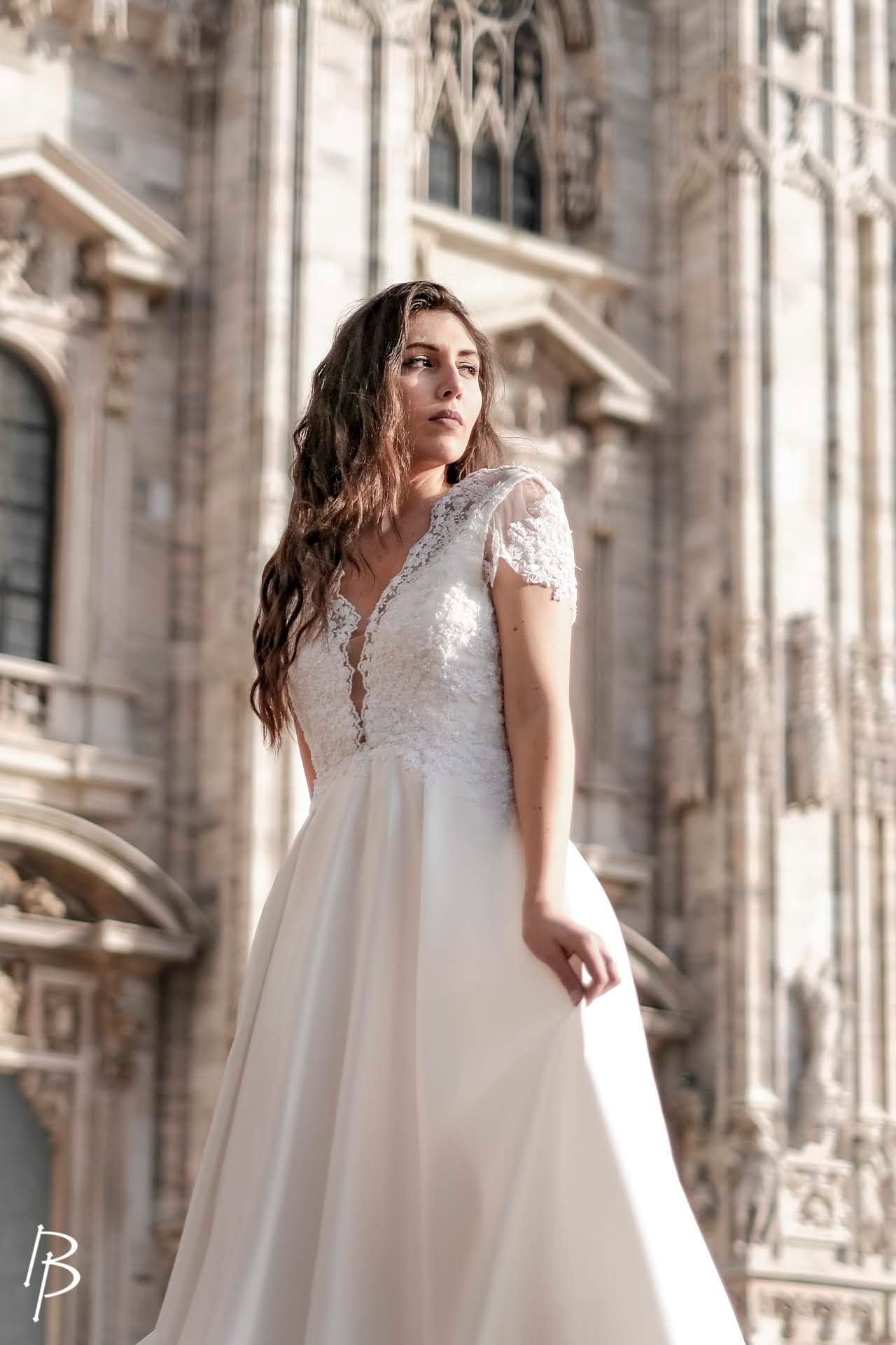 Una donna in abito da sposa è in piedi davanti a un edificio.