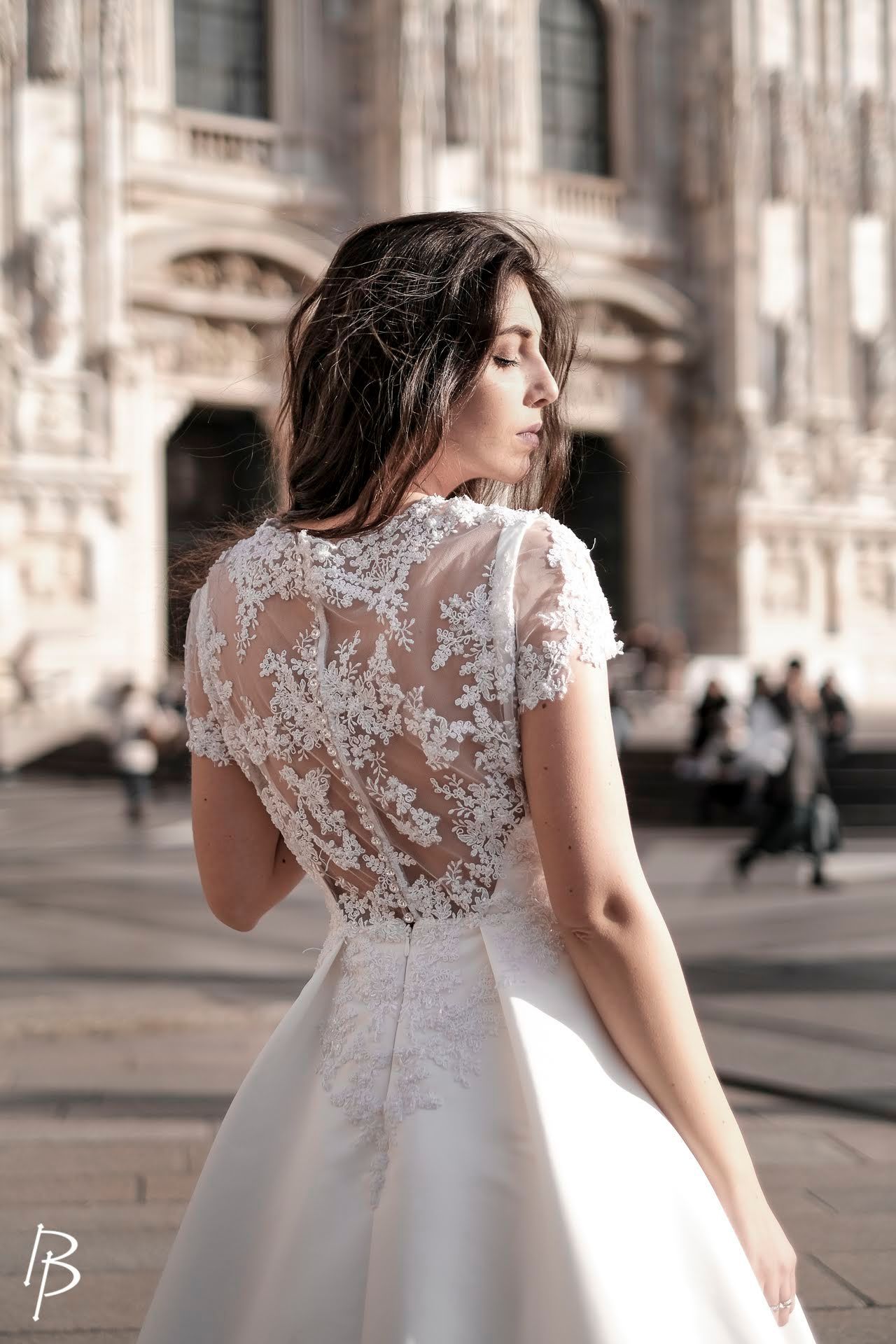 Una donna in abito da sposa è in piedi davanti a un edificio.