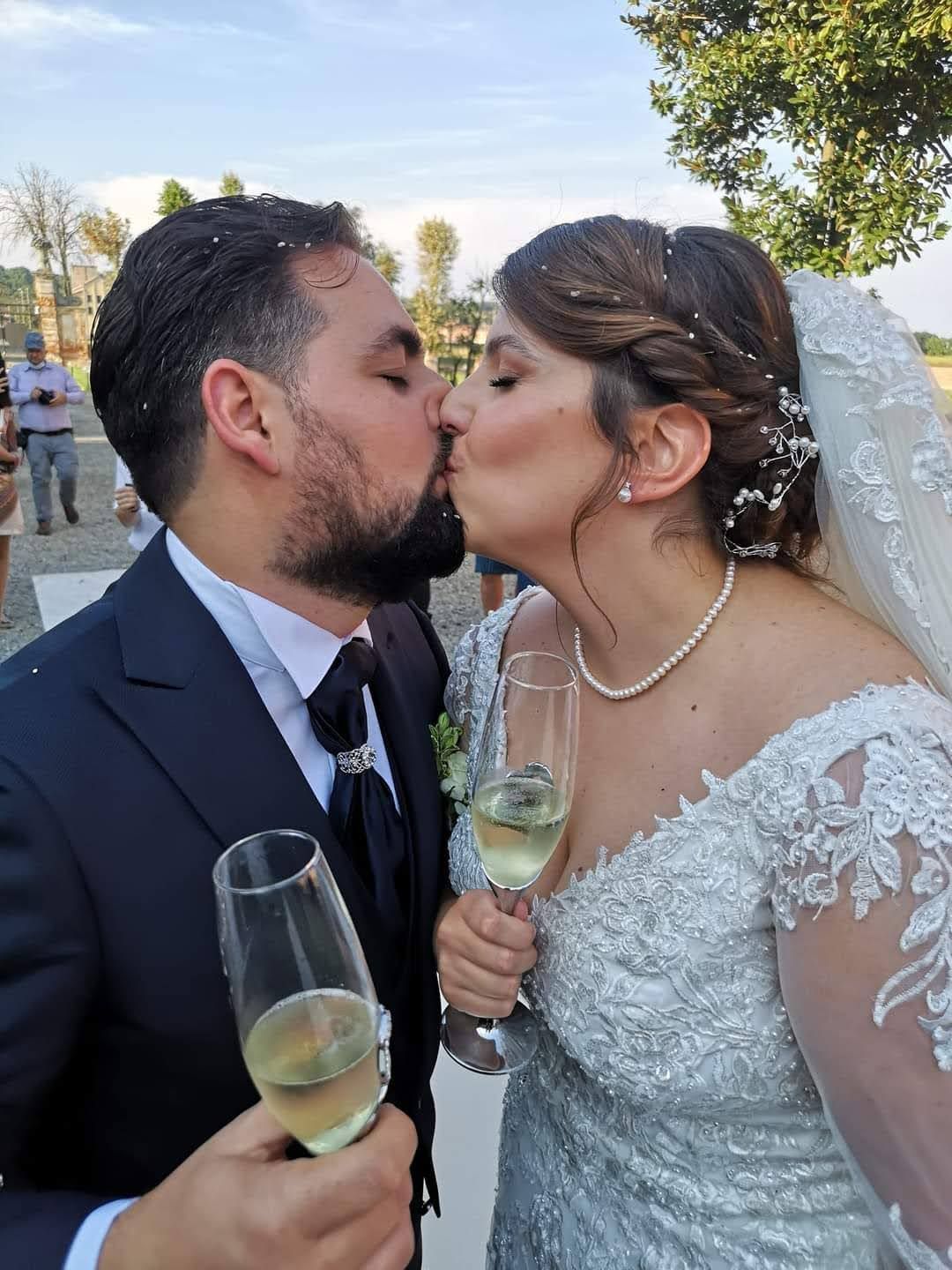 Gli sposi si baciano tenendo in mano dei bicchieri di champagne.