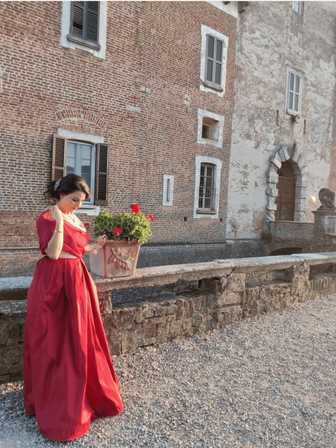 Una donna con un vestito rosso è in piedi davanti a un edificio di mattoni.