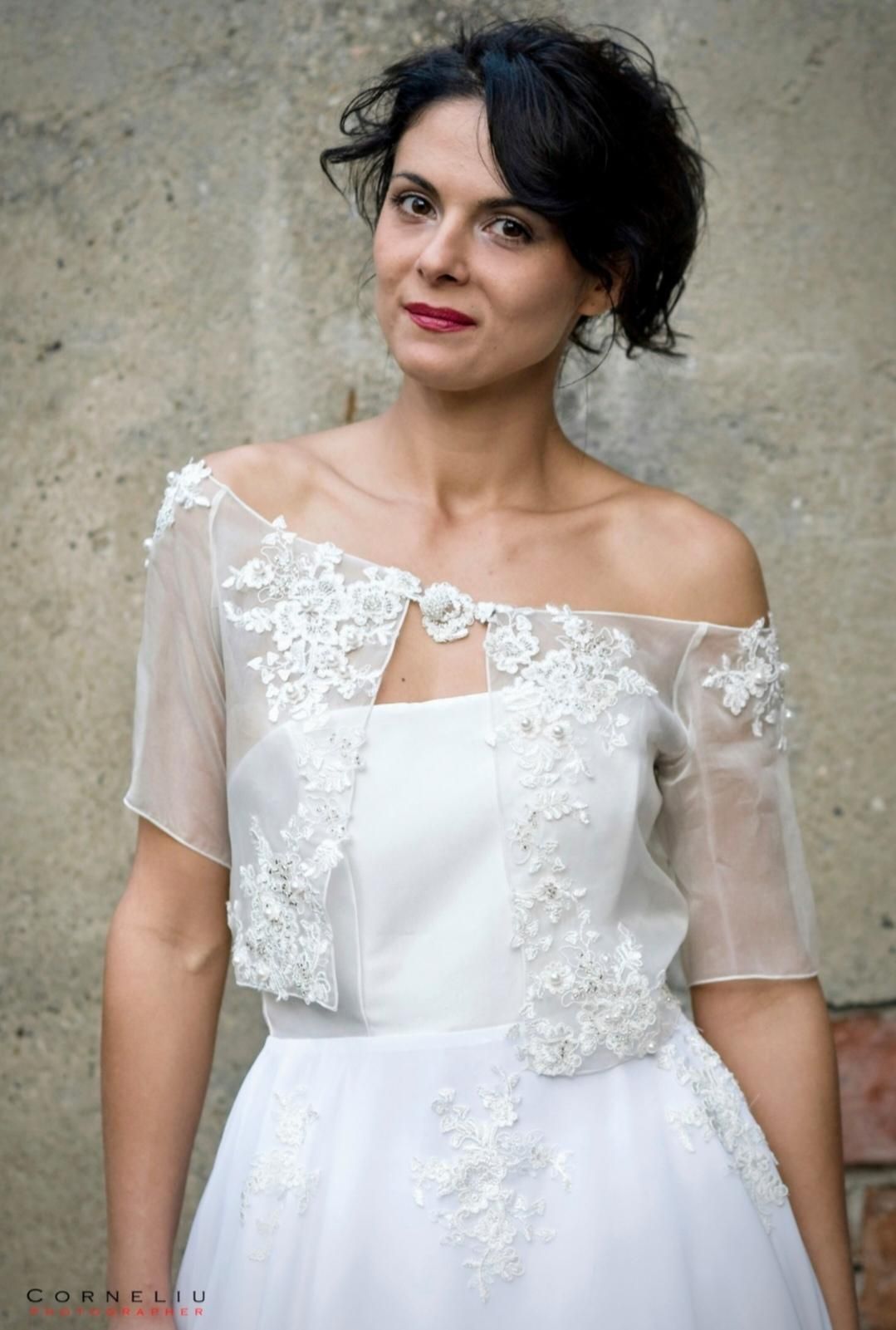 Una donna vestita di bianco è in piedi davanti a un muro.