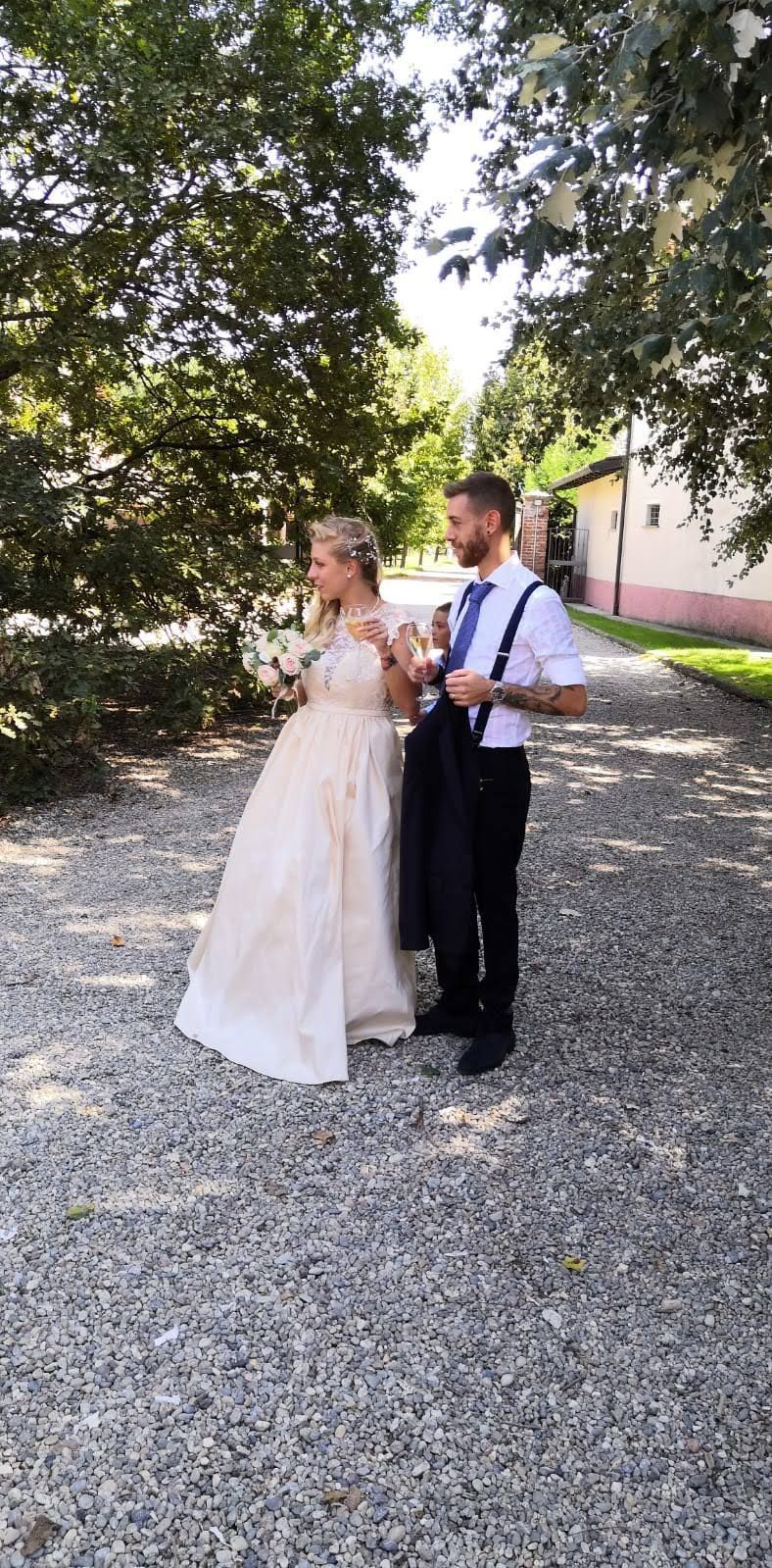 Una sposa e uno sposo sono in piedi uno accanto all'altro su una strada sterrata.