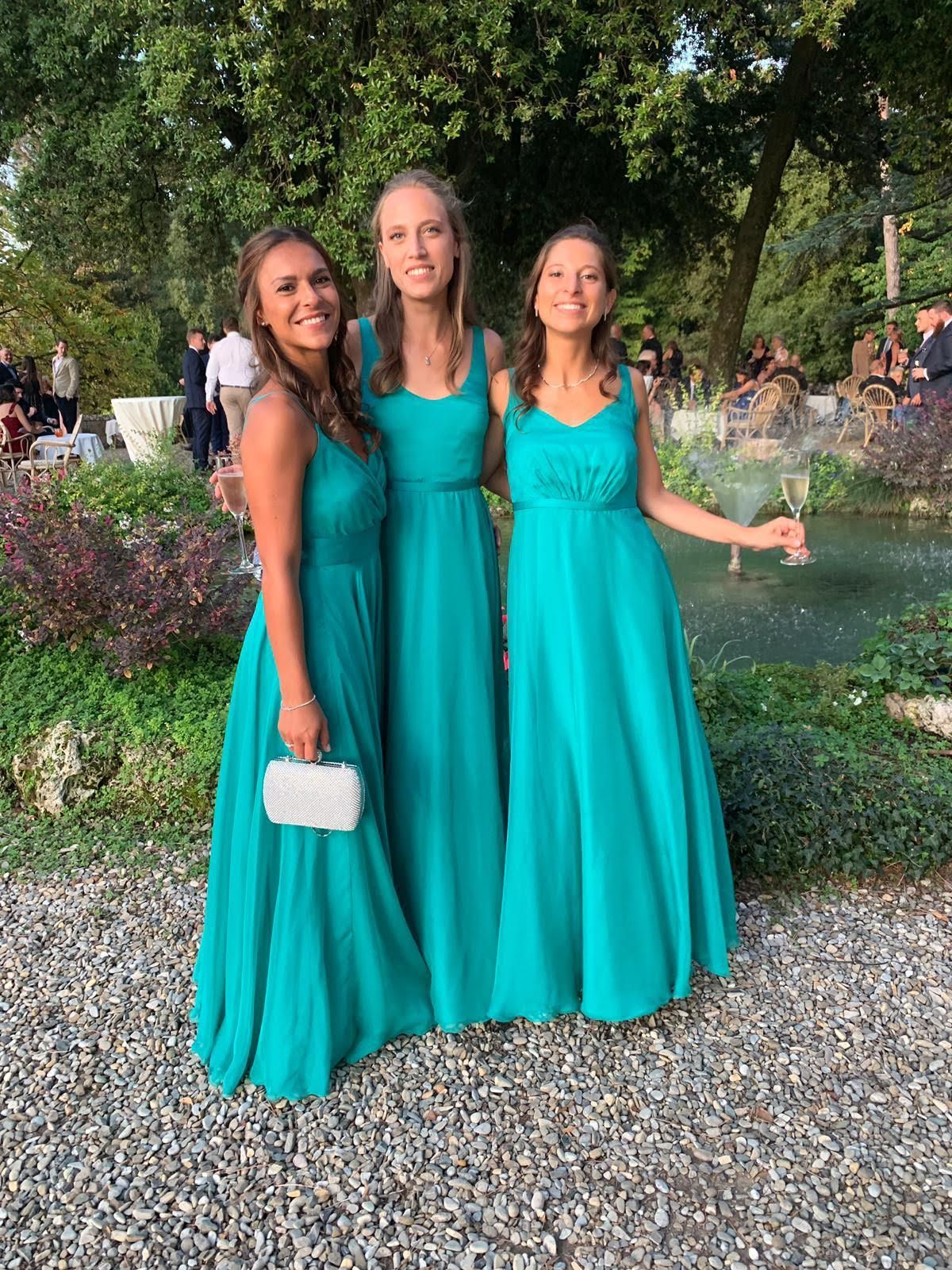 Tre damigelle in abiti color verde acqua posano per una foto.