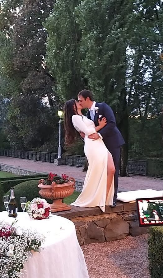 Una sposa e uno sposo che si baciano davanti a un tavolo decorato con fiori