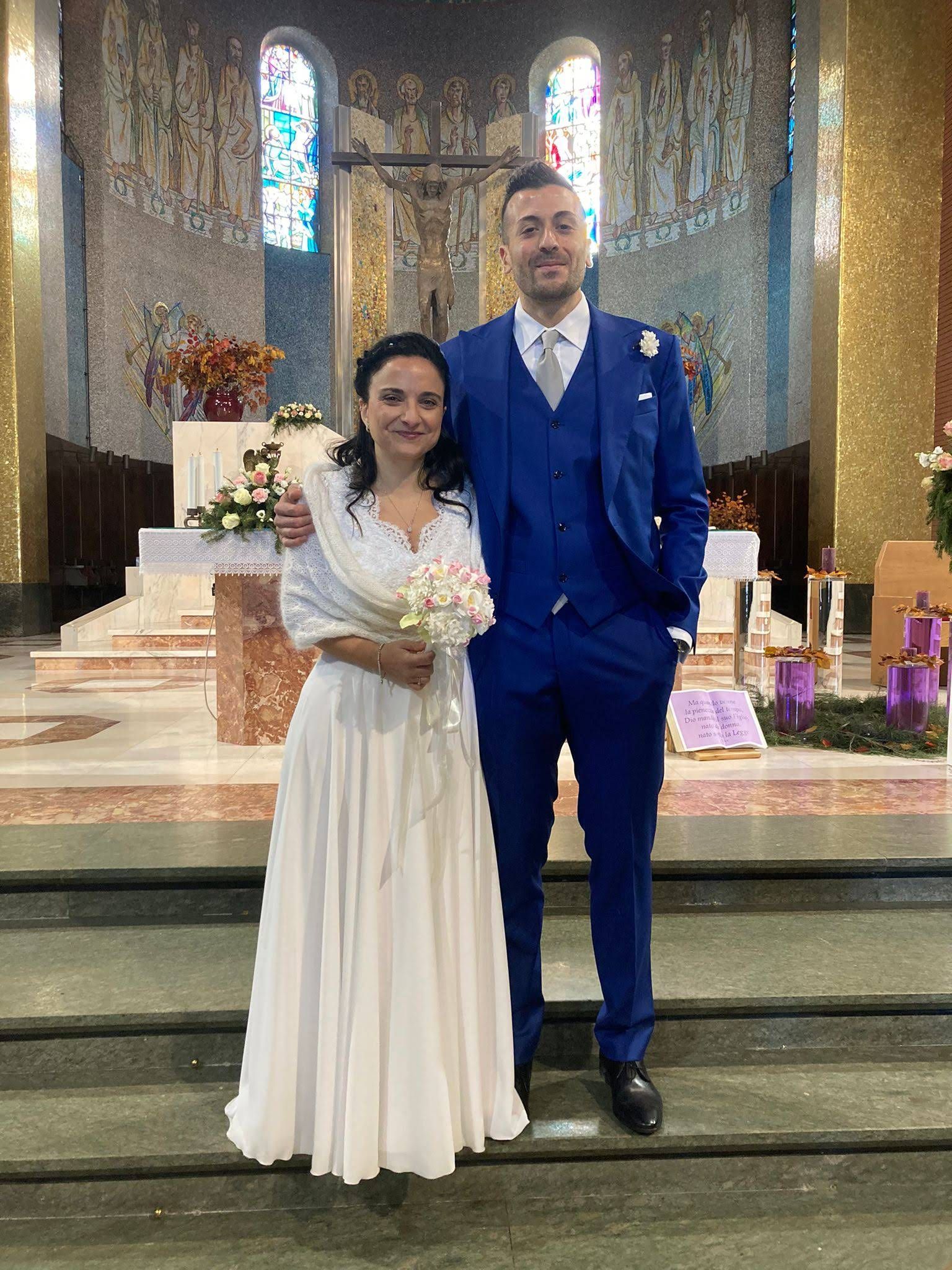 Una coppia di sposi posa per una foto davanti a una chiesa.