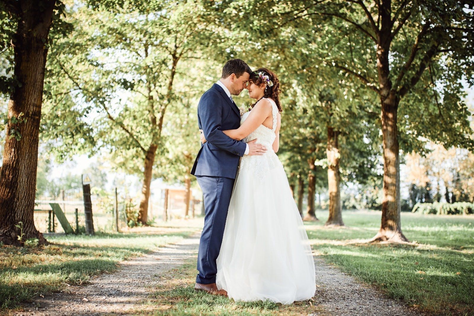 Una sposa e uno sposo sono in piedi uno accanto all'altro in un parco.