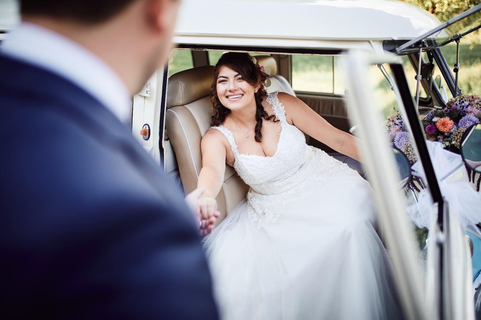 Una sposa è seduta sul sedile posteriore di un'auto e tiene la mano del suo sposo.