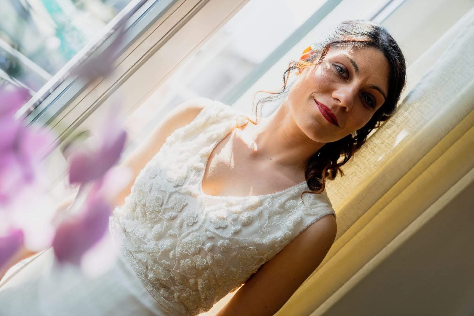 Una donna vestita di bianco è in piedi davanti a una finestra.