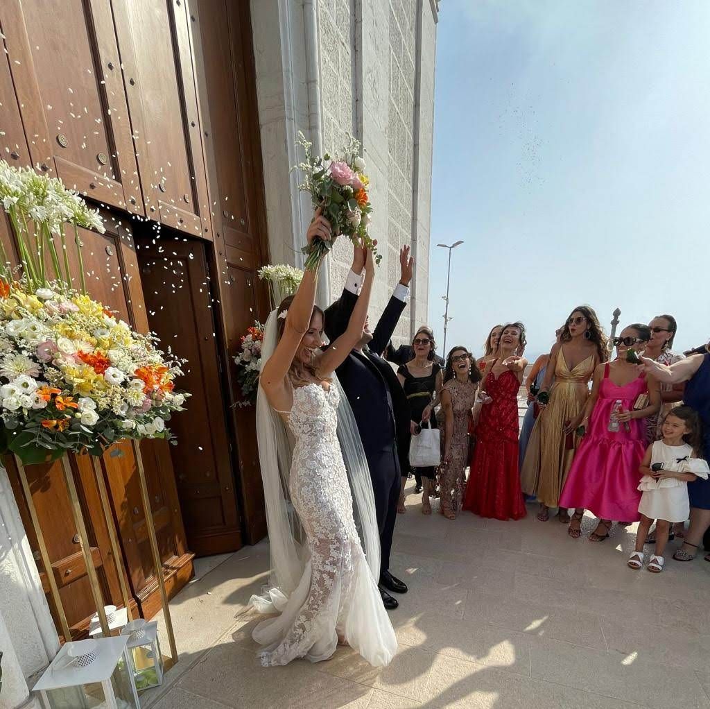 Uno sposo e una sposa si lanciano del riso fuori da una chiesa.