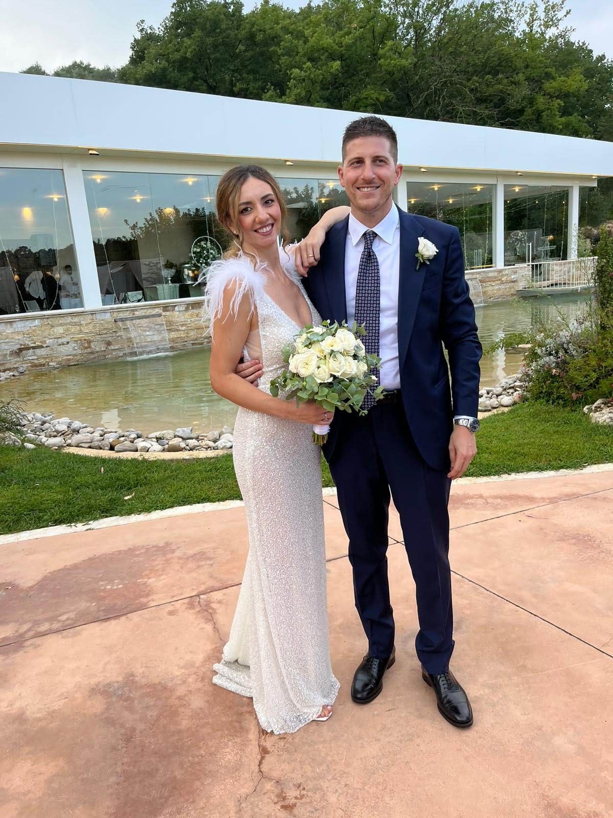 Una coppia di sposi posa per una foto davanti a un edificio.