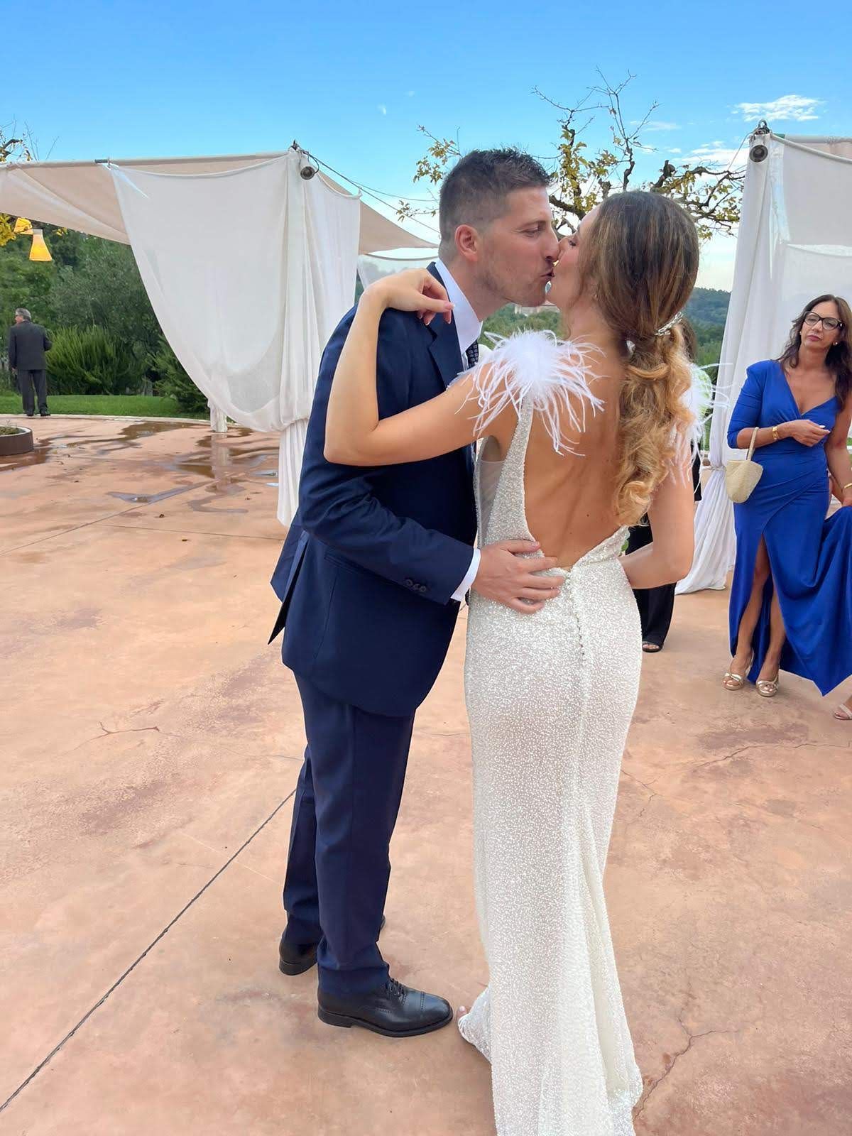 Una sposa e uno sposo si baciano davanti agli invitati alle loro nozze.