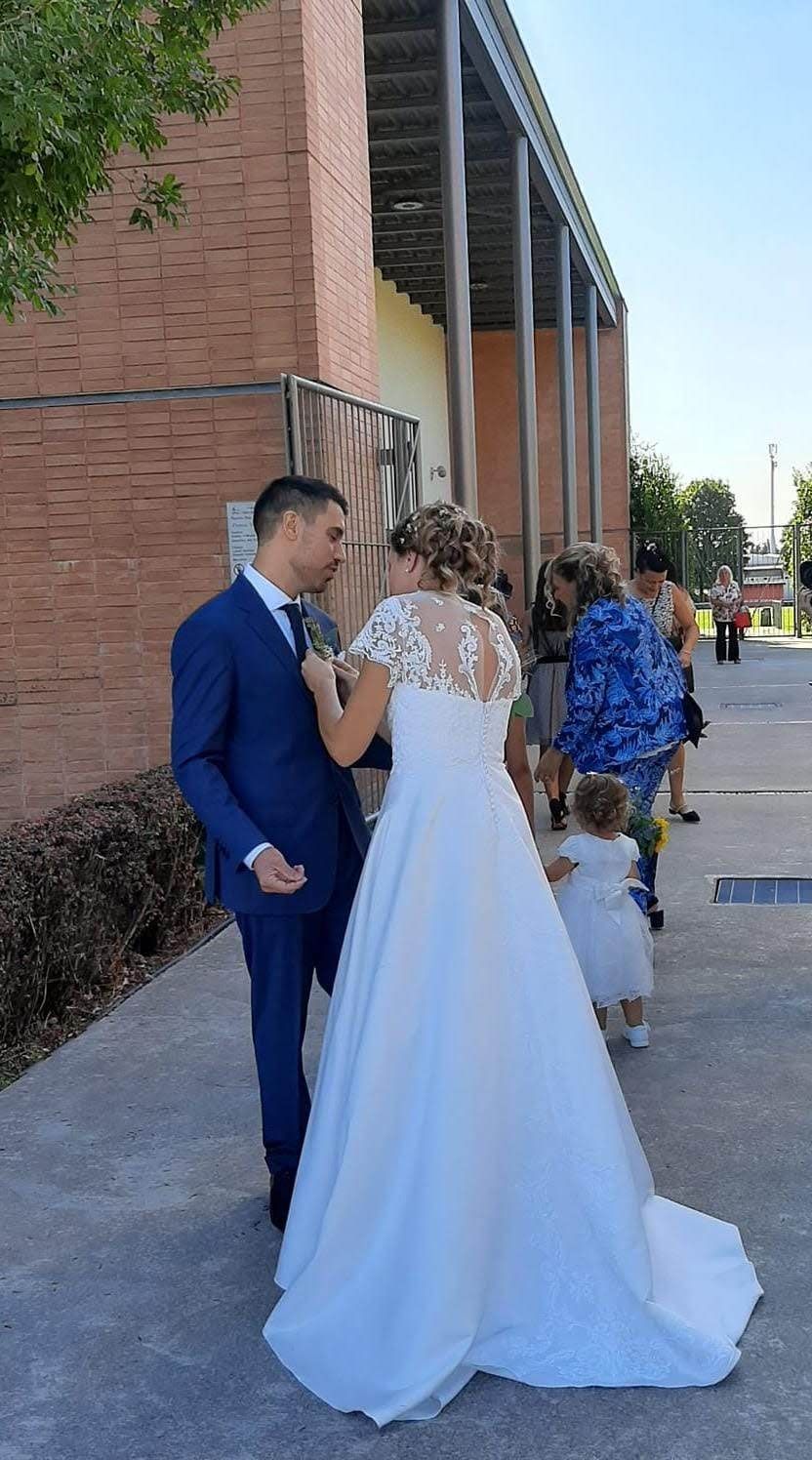 Una sposa e uno sposo sono in piedi uno accanto all'altro su un marciapiede.