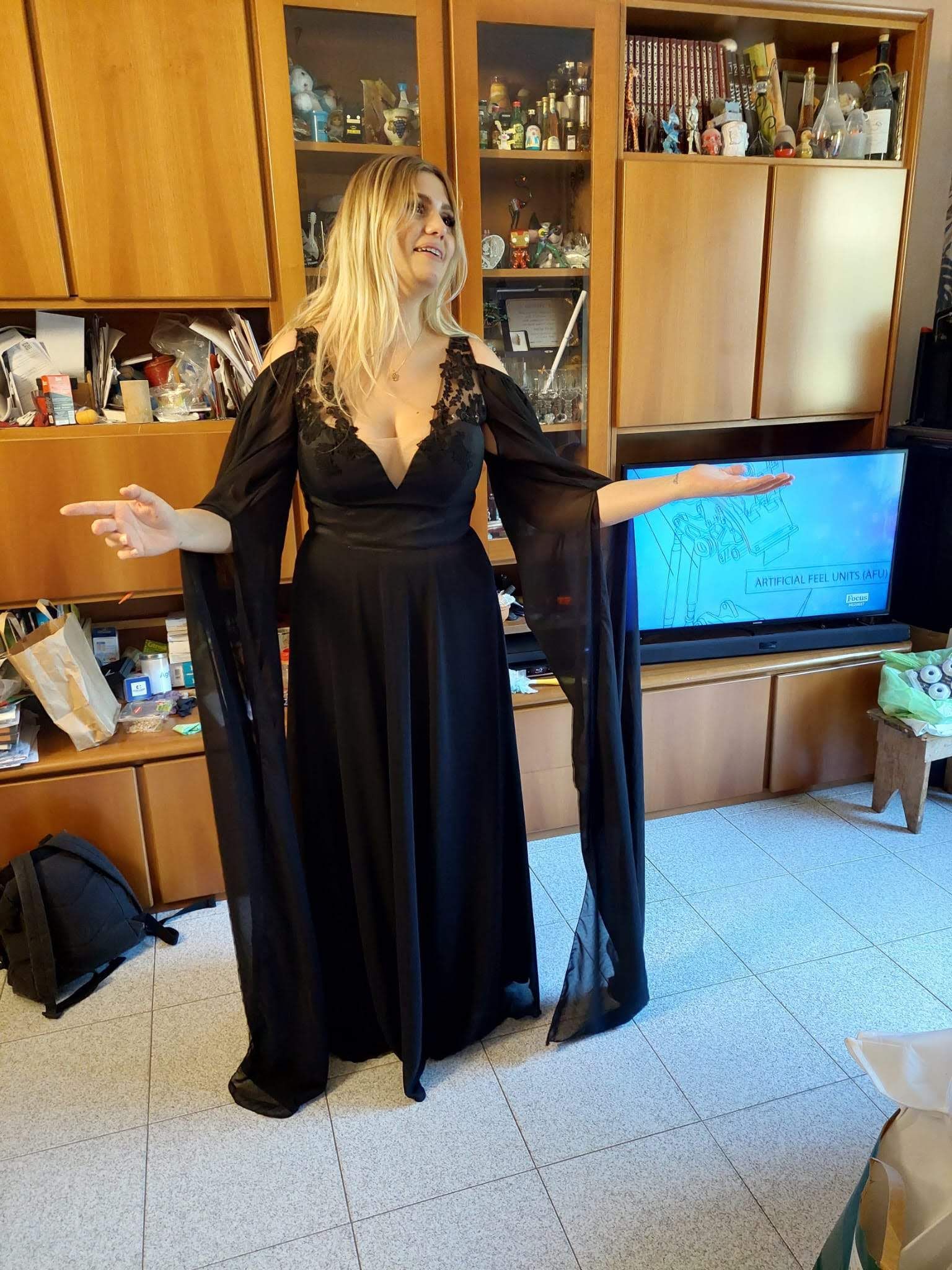 Una donna con un abito nero è in piedi in un soggiorno.