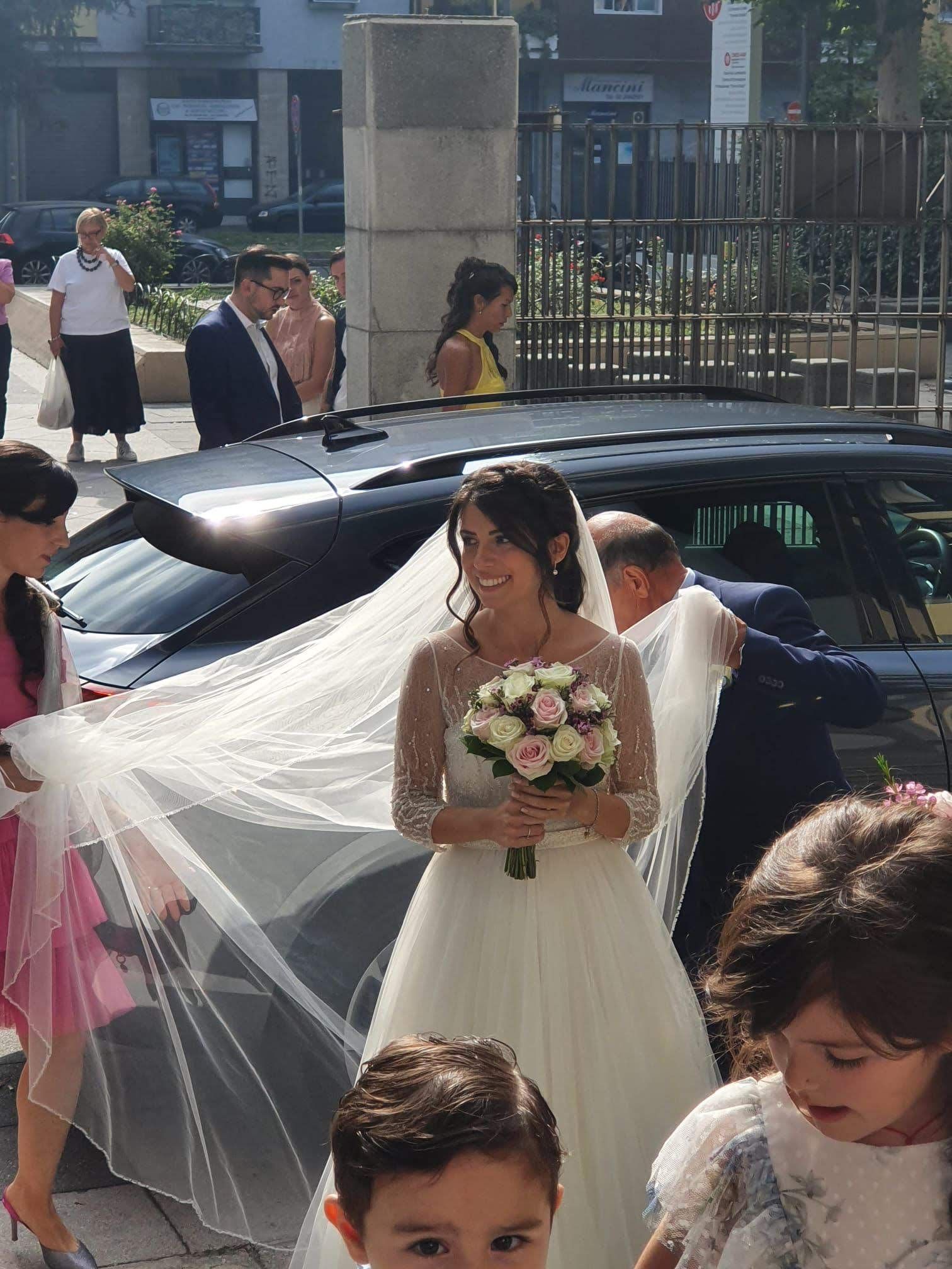 Una donna in abito da sposa tiene in mano un mazzo di fiori
