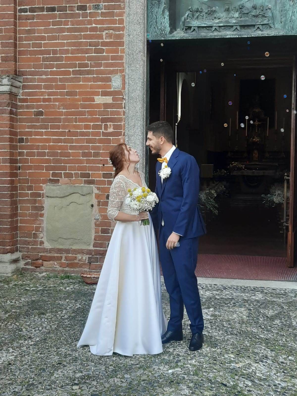 Una sposa e uno sposo sono in piedi davanti a un edificio in mattoni.