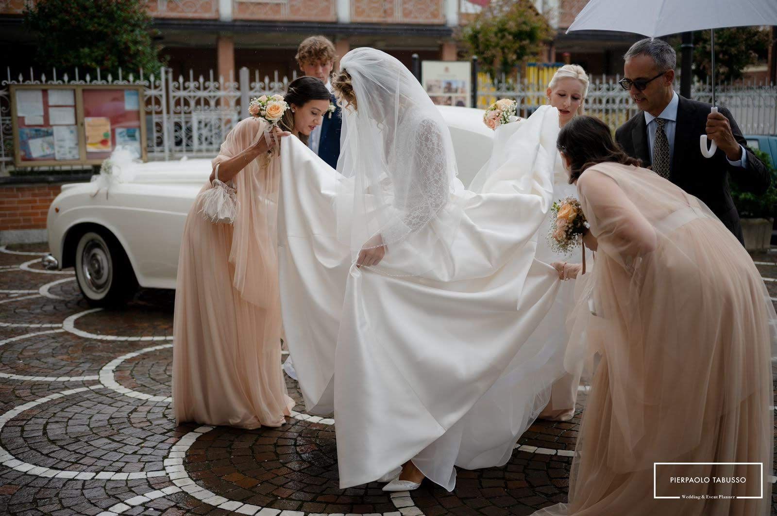 Una sposa e le sue damigelle sono in piedi davanti a un'auto bianca.