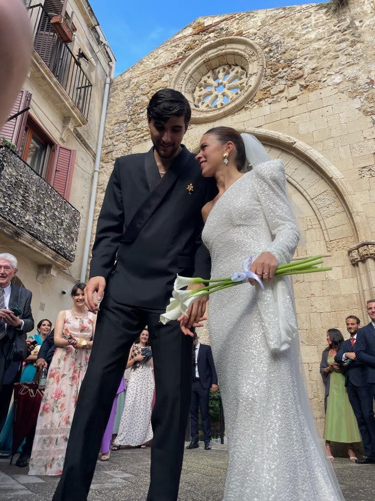 Una coppia di sposi posa per una foto davanti a una chiesa.
