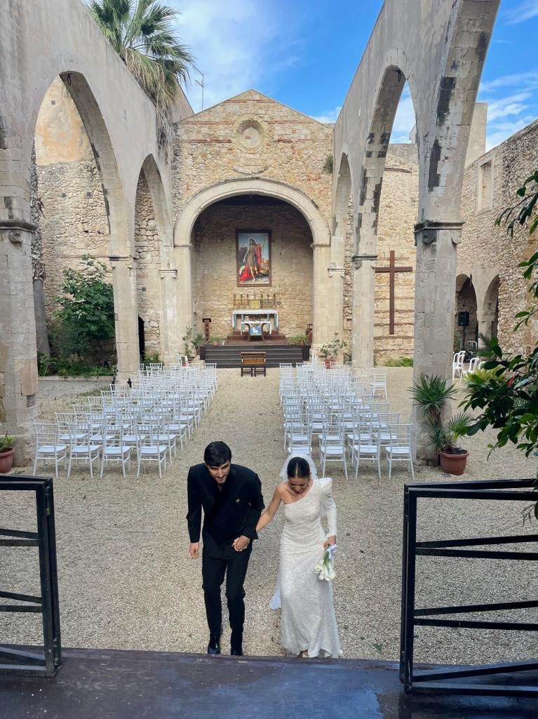 Una sposa e uno sposo stanno camminando lungo la navata di una chiesa.