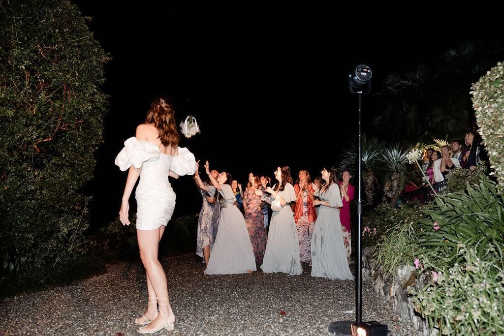Una donna vestita di bianco lancia in aria un mazzo di fiori.