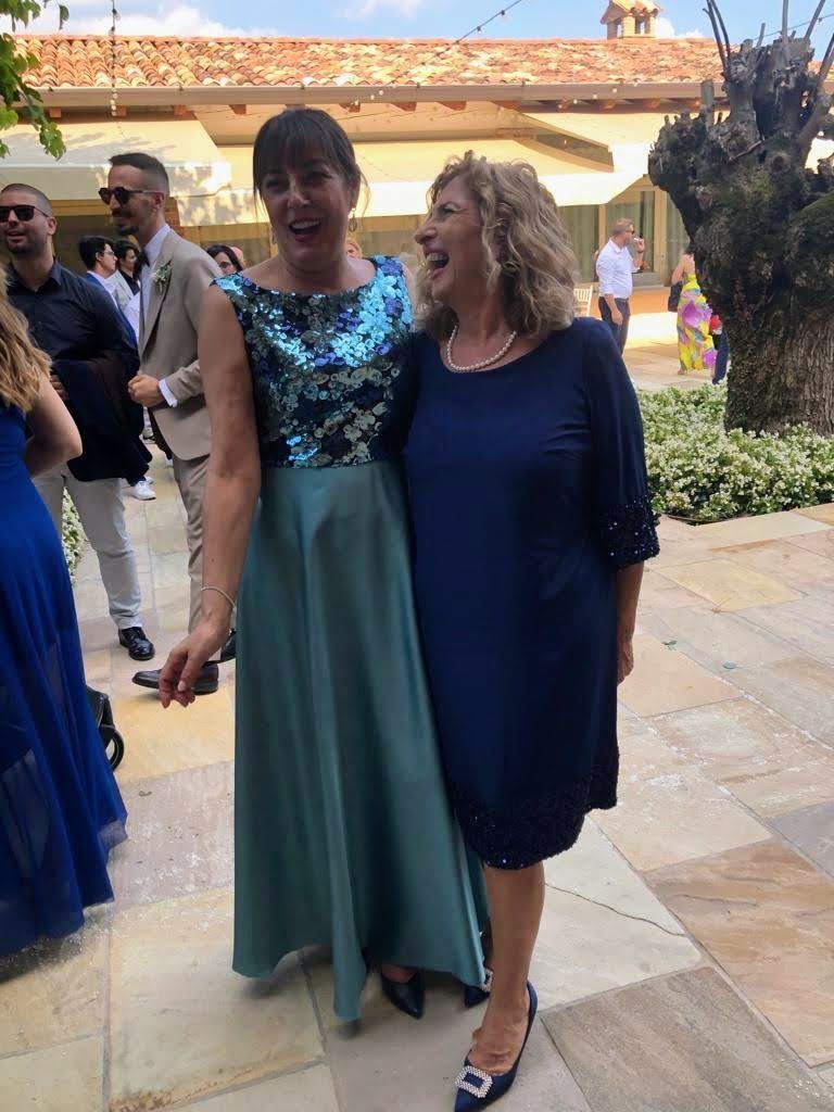 Due donne in abiti blu sono in piedi una accanto all'altra su un marciapiede.