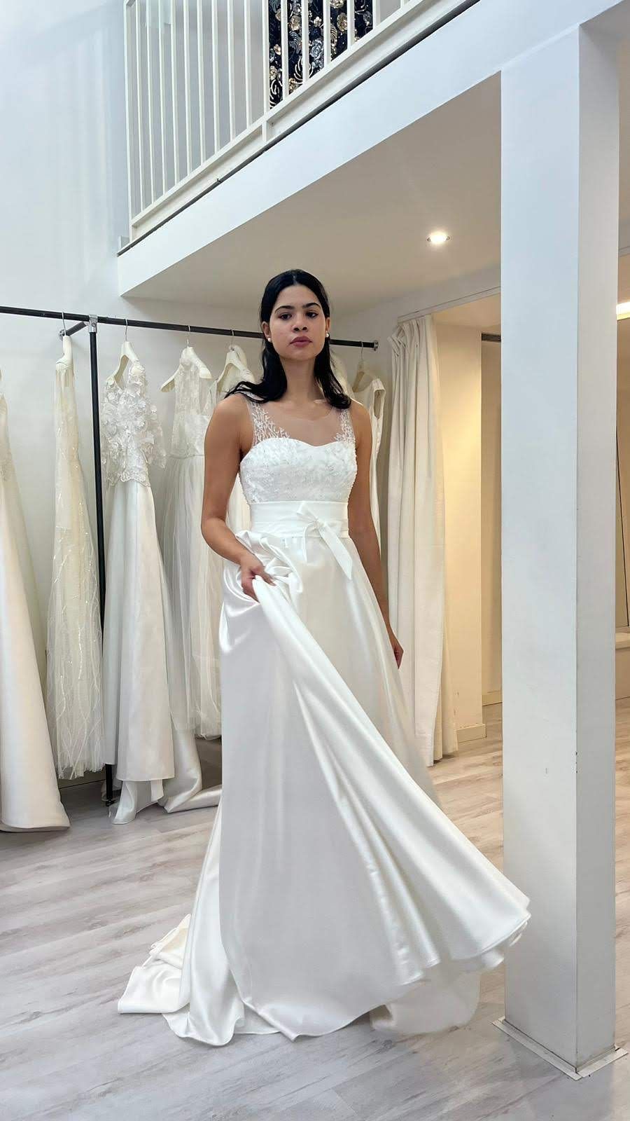 Una donna in abito da sposa bianco è in piedi in una stanza.