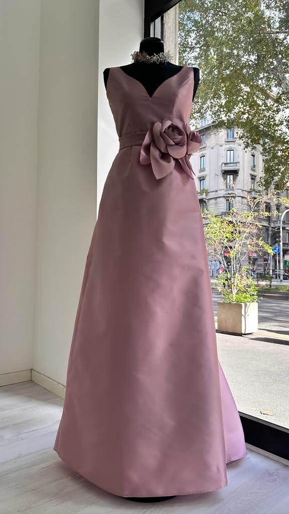 Un vestito rosa è su un manichino davanti a una finestra.