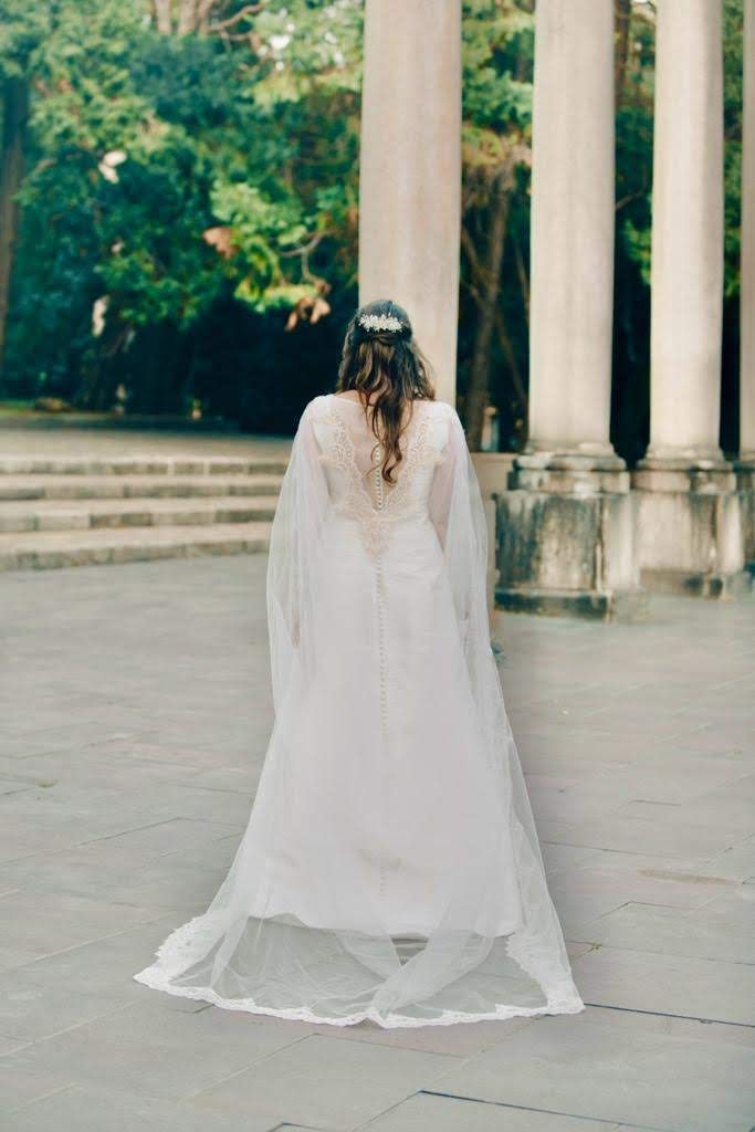 Una sposa in abito da sposa e velo è in piedi davanti a una fila di colonne.