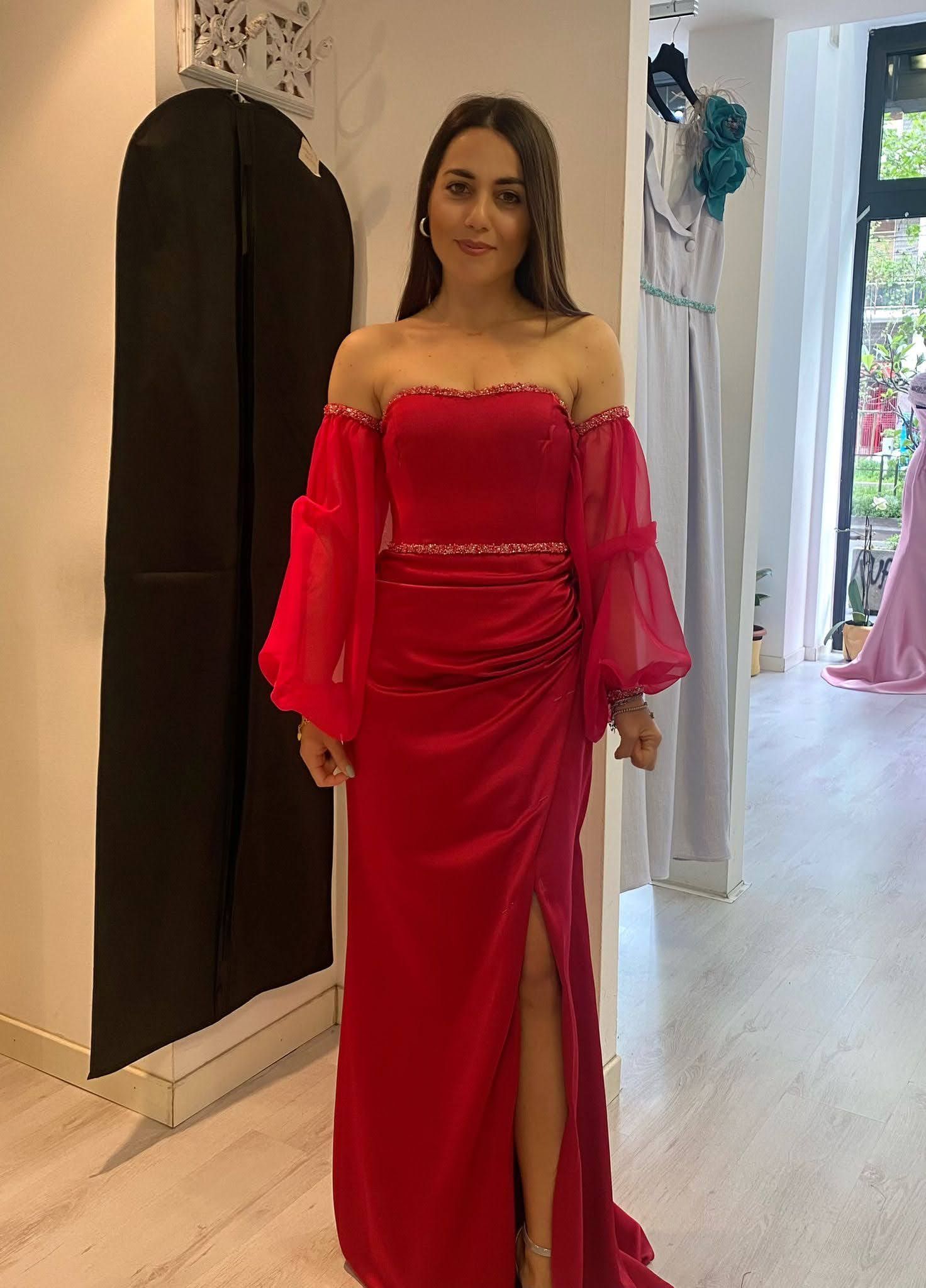 Una donna con un vestito rosso è in piedi in una stanza.