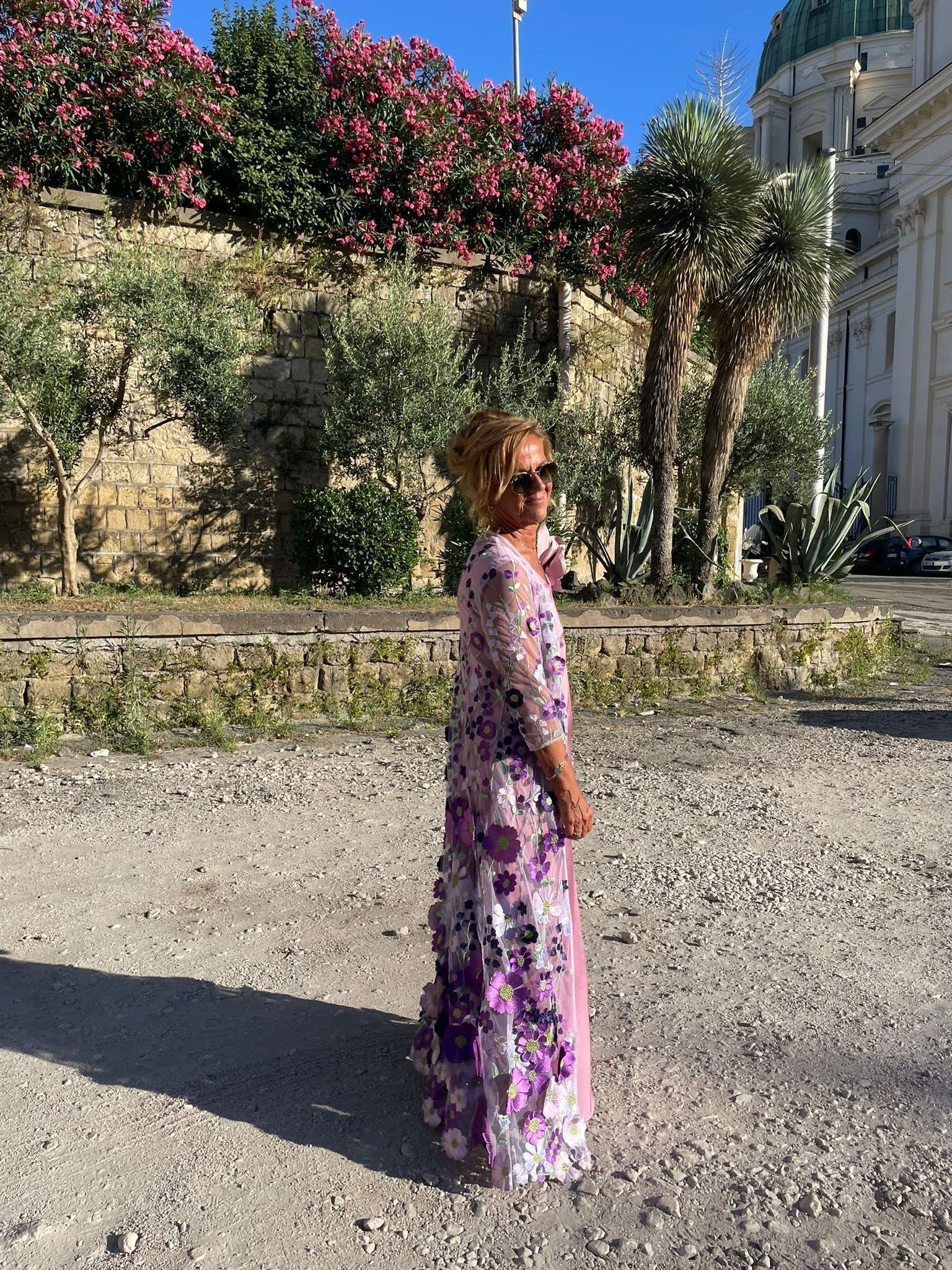 Una donna con un lungo abito viola è in piedi davanti a un edificio.