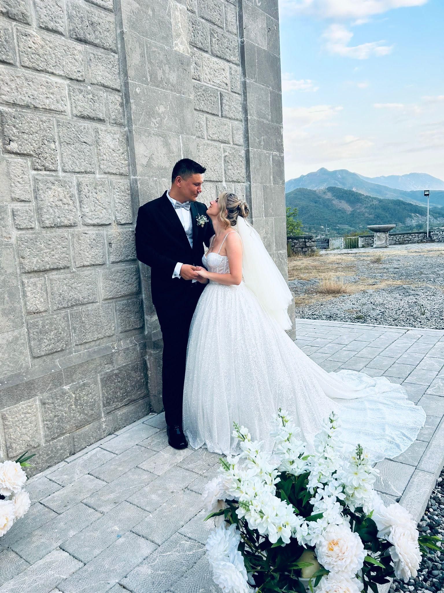 Una coppia di sposi posa per una foto davanti a un muro di mattoni.