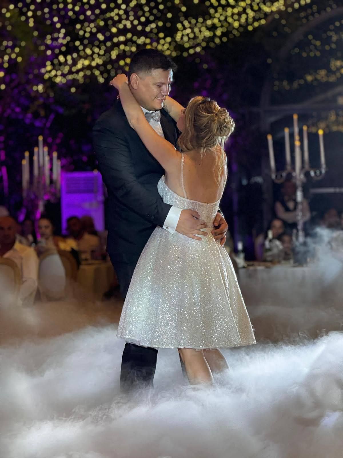 Una coppia di sposi balla nella nebbia durante il ricevimento di nozze.