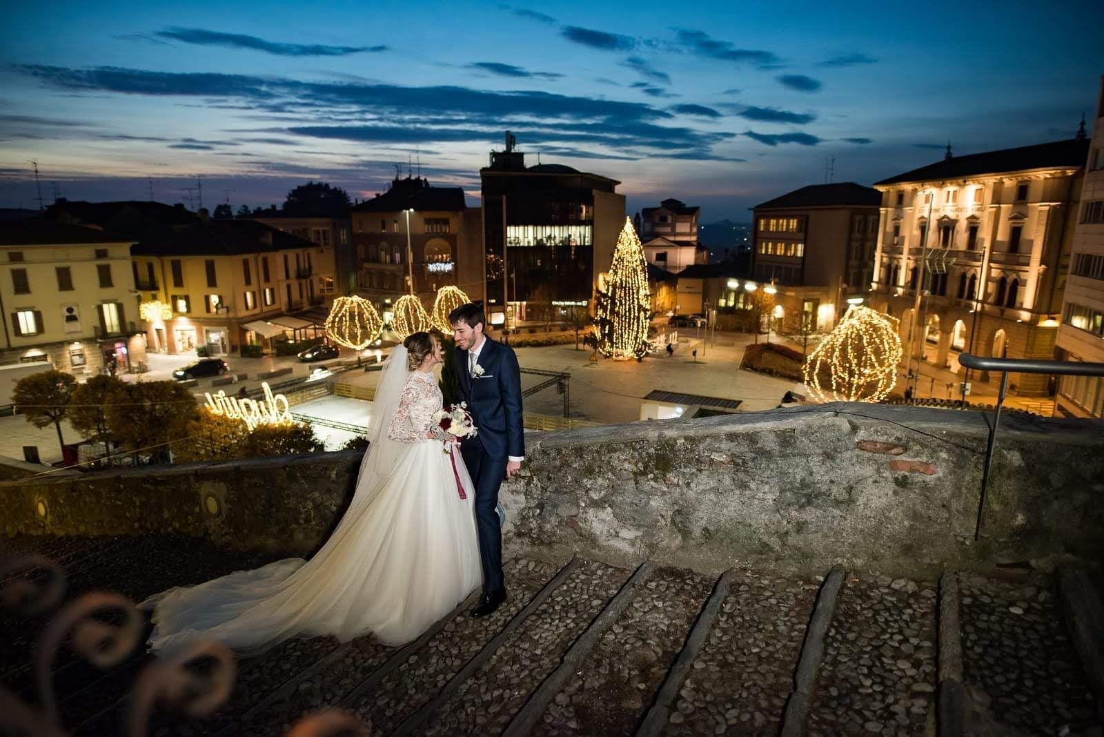 Una coppia di sposi è in piedi su una scalinata davanti all'albero di Natale.